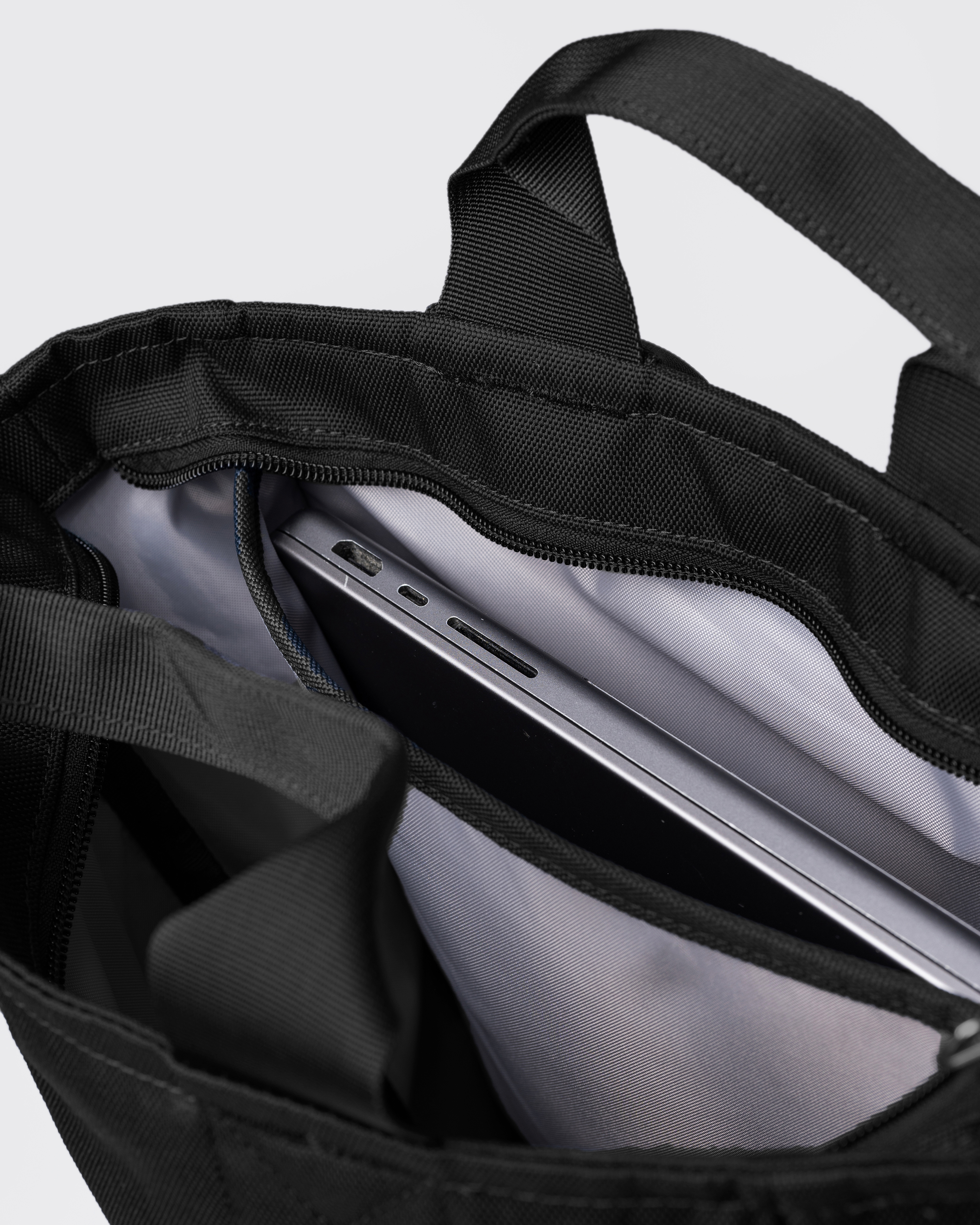 Sandqvist Ground 2-way Bag, black. Inside view, two handles, main compartment with zipper and laptop compartment with laptop in it.