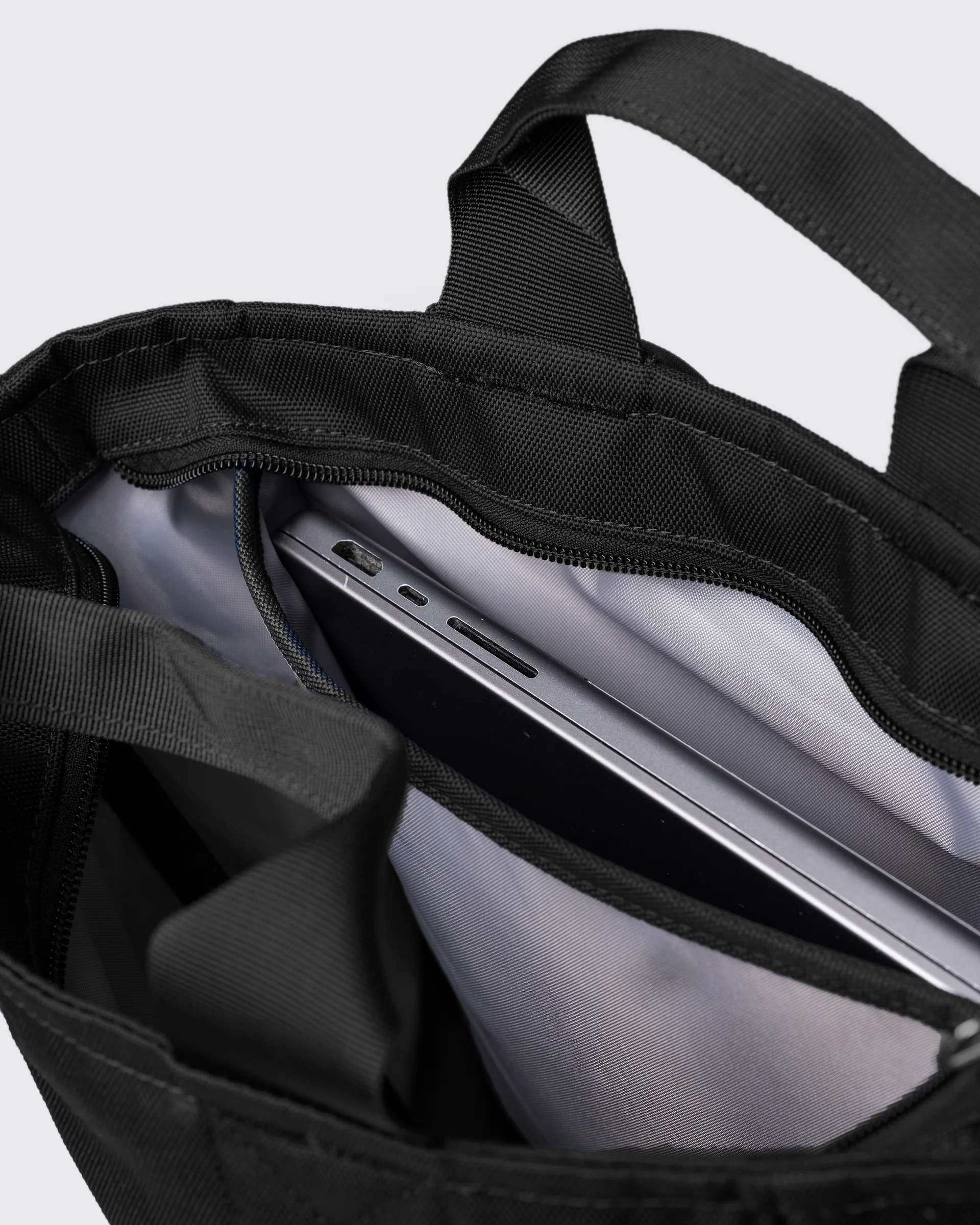 Sandqvist Ground 2-way Bag, black. Inside view, two handles, main compartment with zipper and laptop compartment with laptop in it.