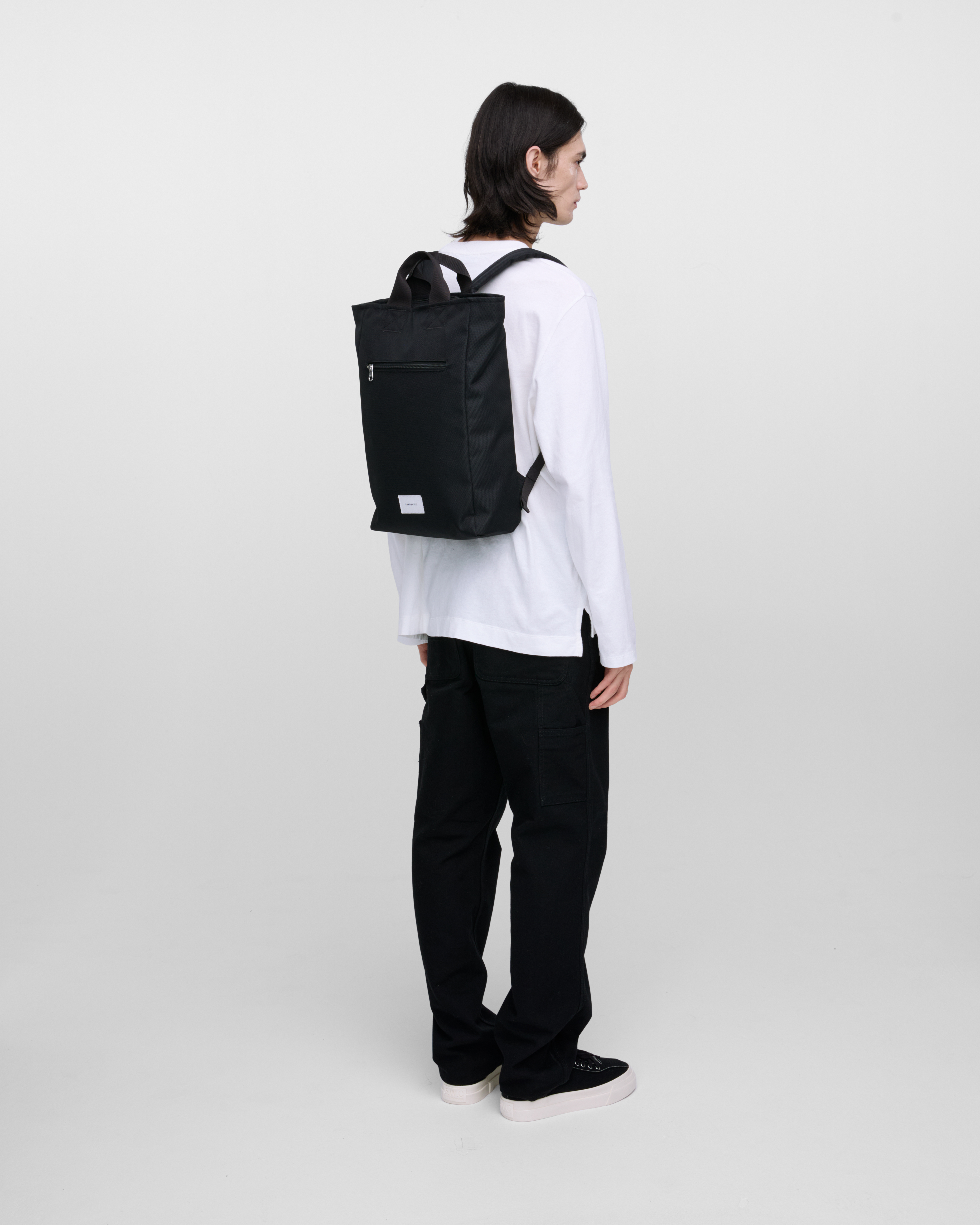 Male model wearing Sandqvist Ground 2-way Bag, black. Back view, wearing the bag on the back.