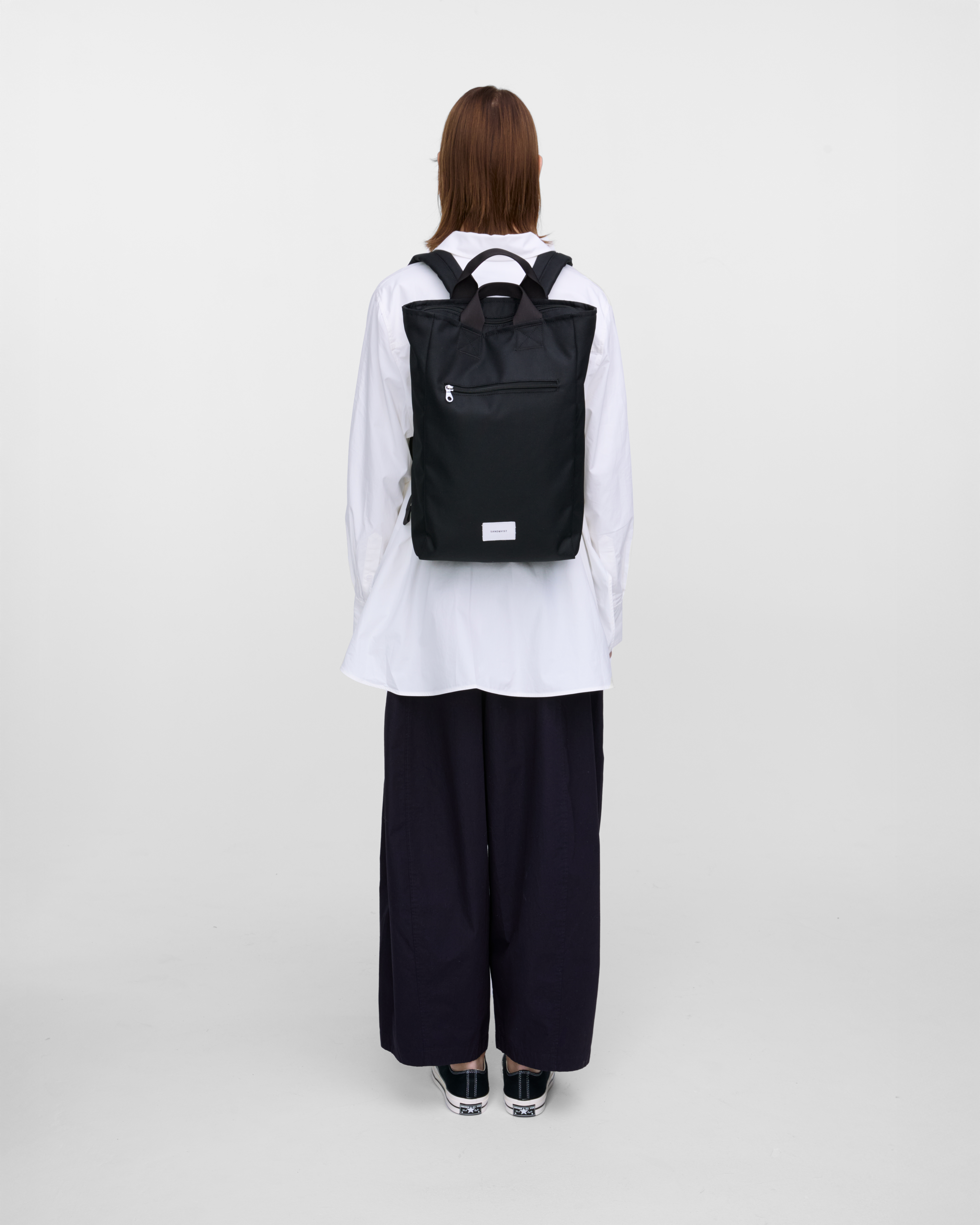 Female model wearing Sandqvist Ground 2-way Bag, black. Back view, wearing the bag on the back.