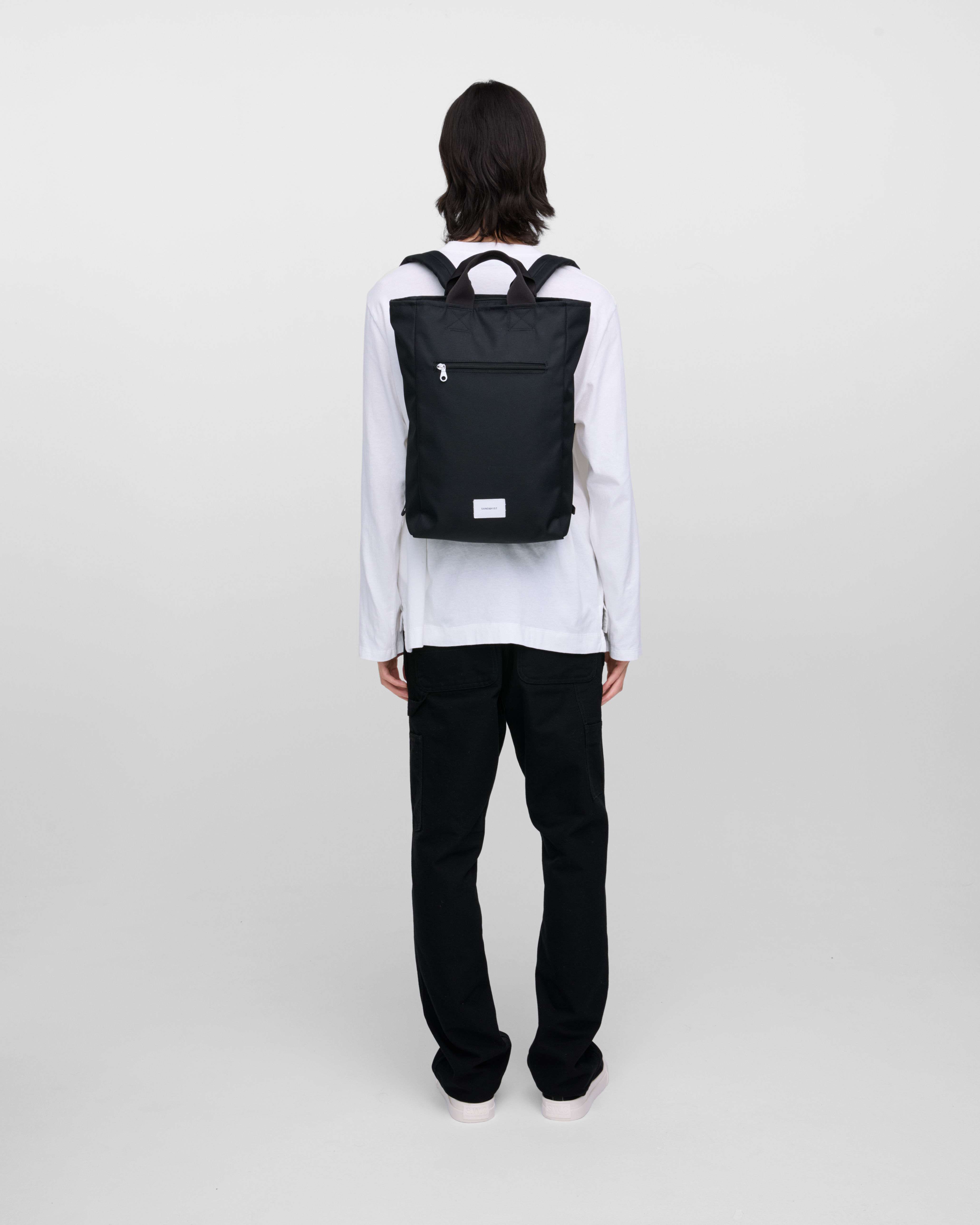 Male model wearing Sandqvist Ground 2-way Bag, black. Back view, wearing the bag on the back.