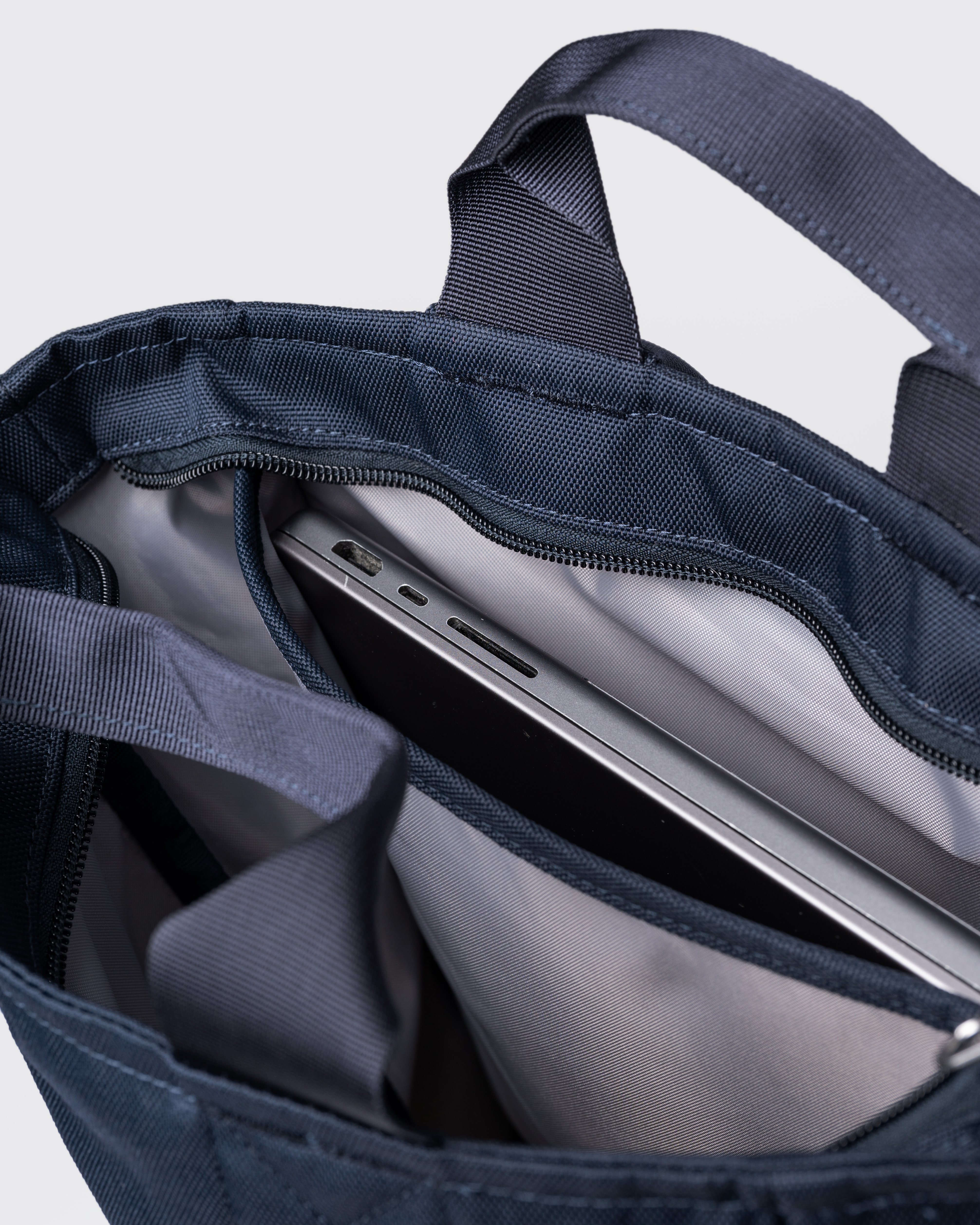 Sandqvist Ground 2-way Bag, blue. Inside view, two handles, main compartment with zipper and laptop compartment with laptop in it.