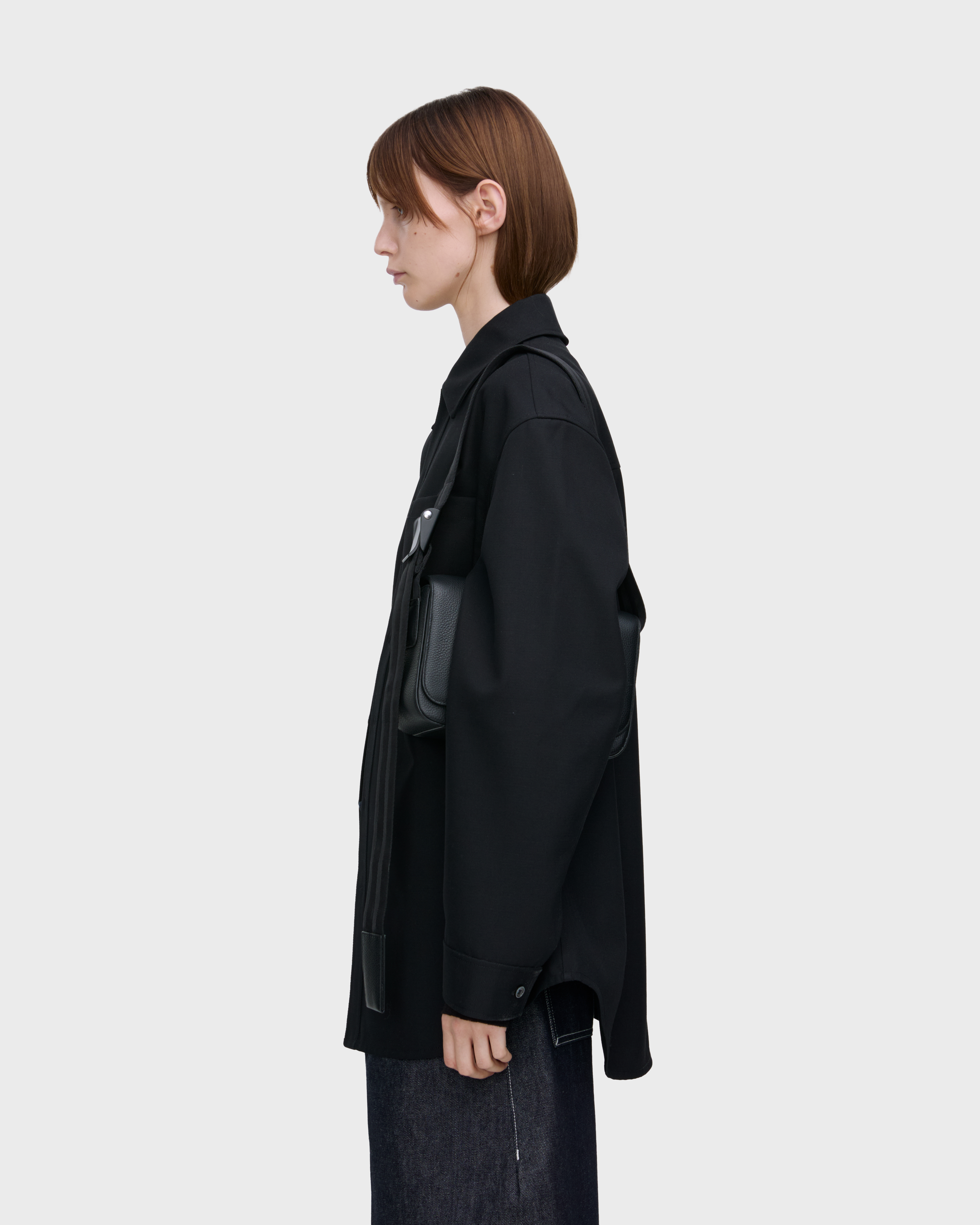 Female model carrying Sandqvist Agile Crossbody Bag, black. Seen from the side, carrying the bag on one shoulder.