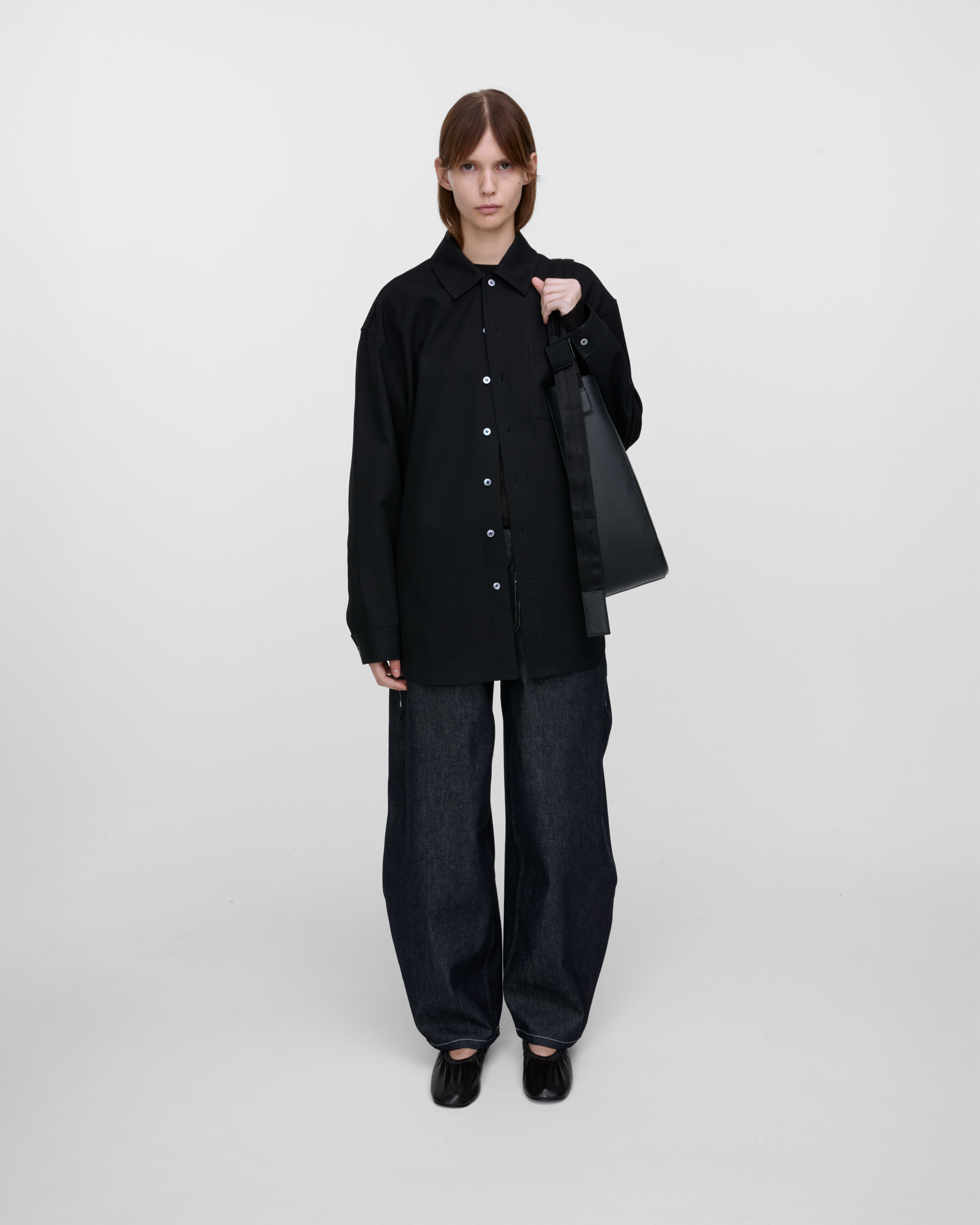 Female model wearing Sandqvist Agile Hobo Tote Bag, black. Front view, wearing the bag on one shoulder.