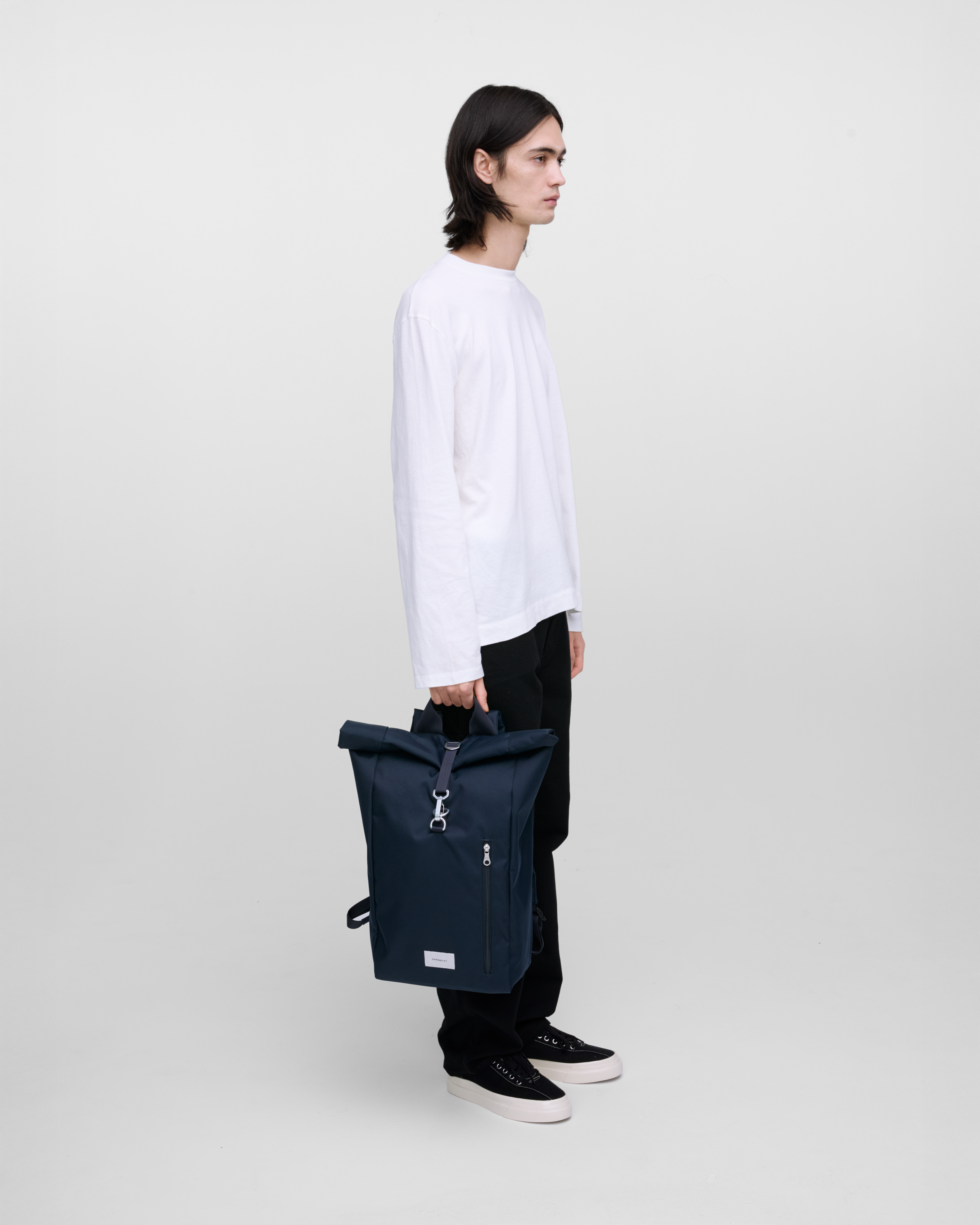Backpack Sandqvist Ground Rolltop Backpack L in Navy, carried by the top handle.