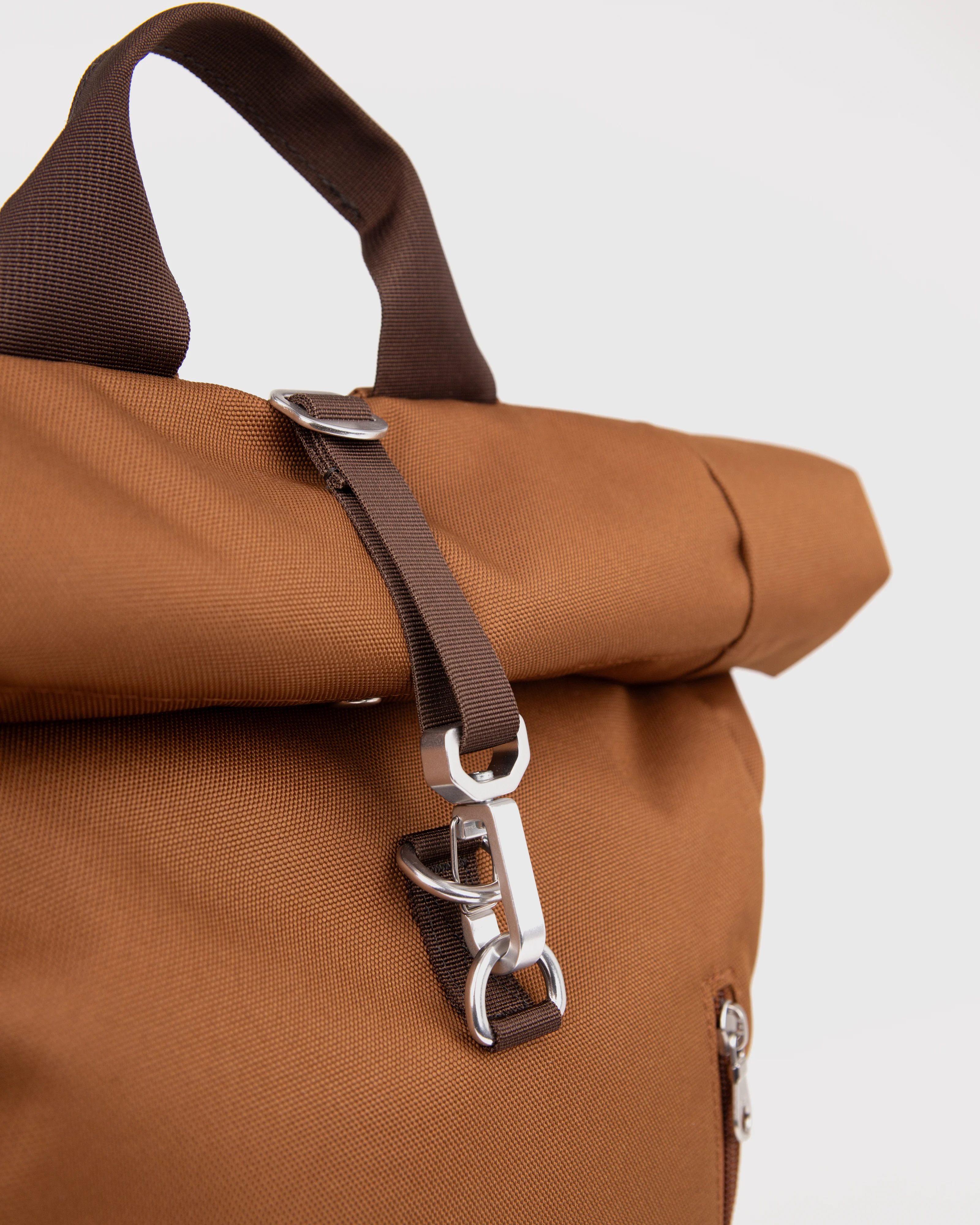Sandqvist Ground Rolltop Backpack L, brown. Close-up of the front buckle and handle.