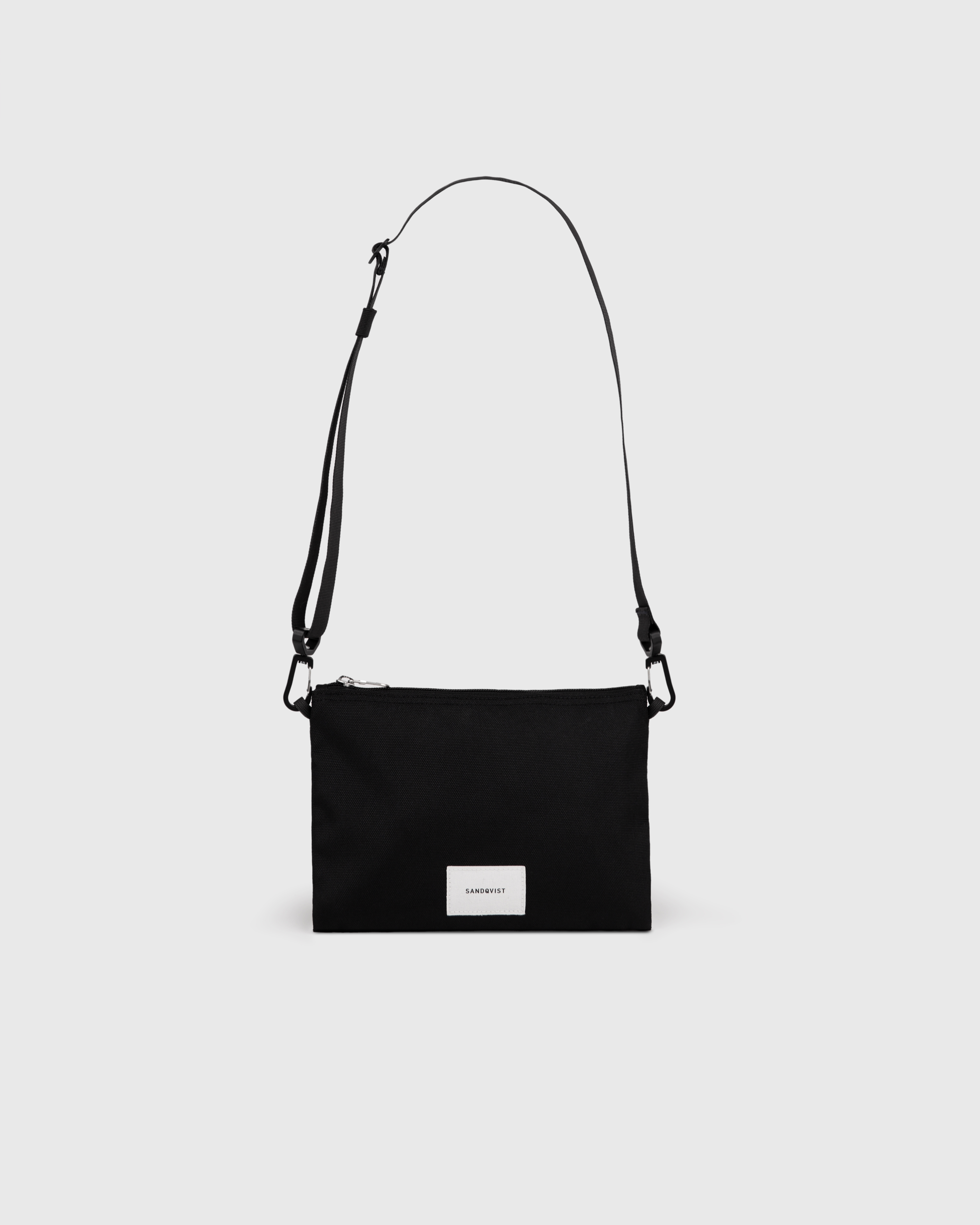 Sandqvist Ground Sacoche Slim, black. Front view, logo, zipper and shoulder strap.