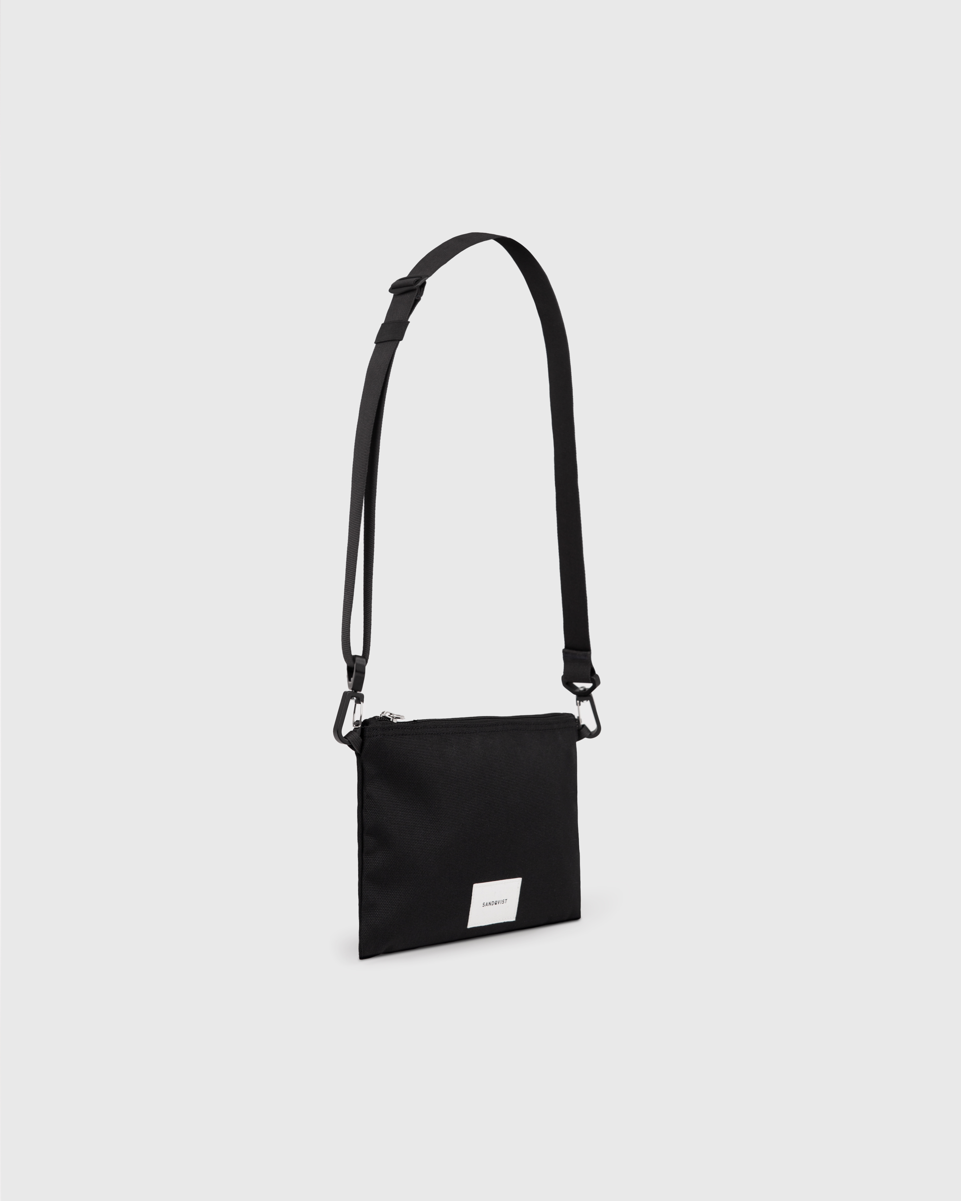 Sandqvist Ground Sacoche Slim, black. Side view, logo, zipper and shoulder strap.
