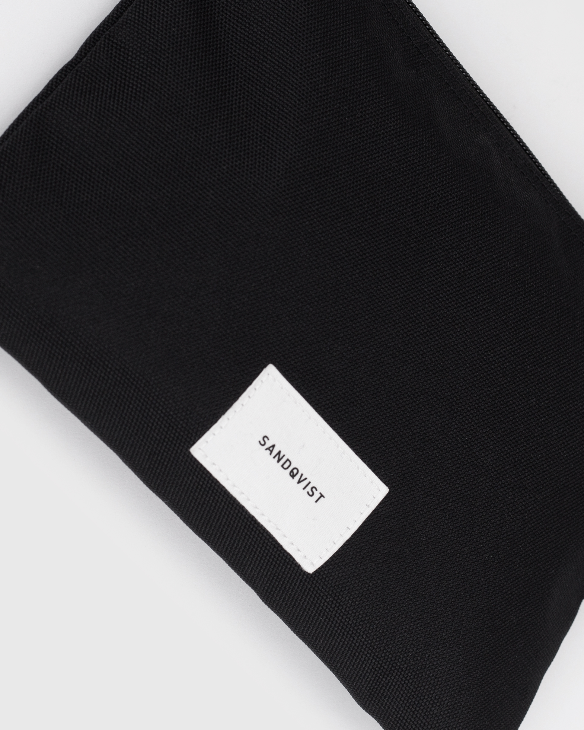 Sandqvist Ground Sacoche Slim, black. Close-up of the Sandqvist logo in the front.