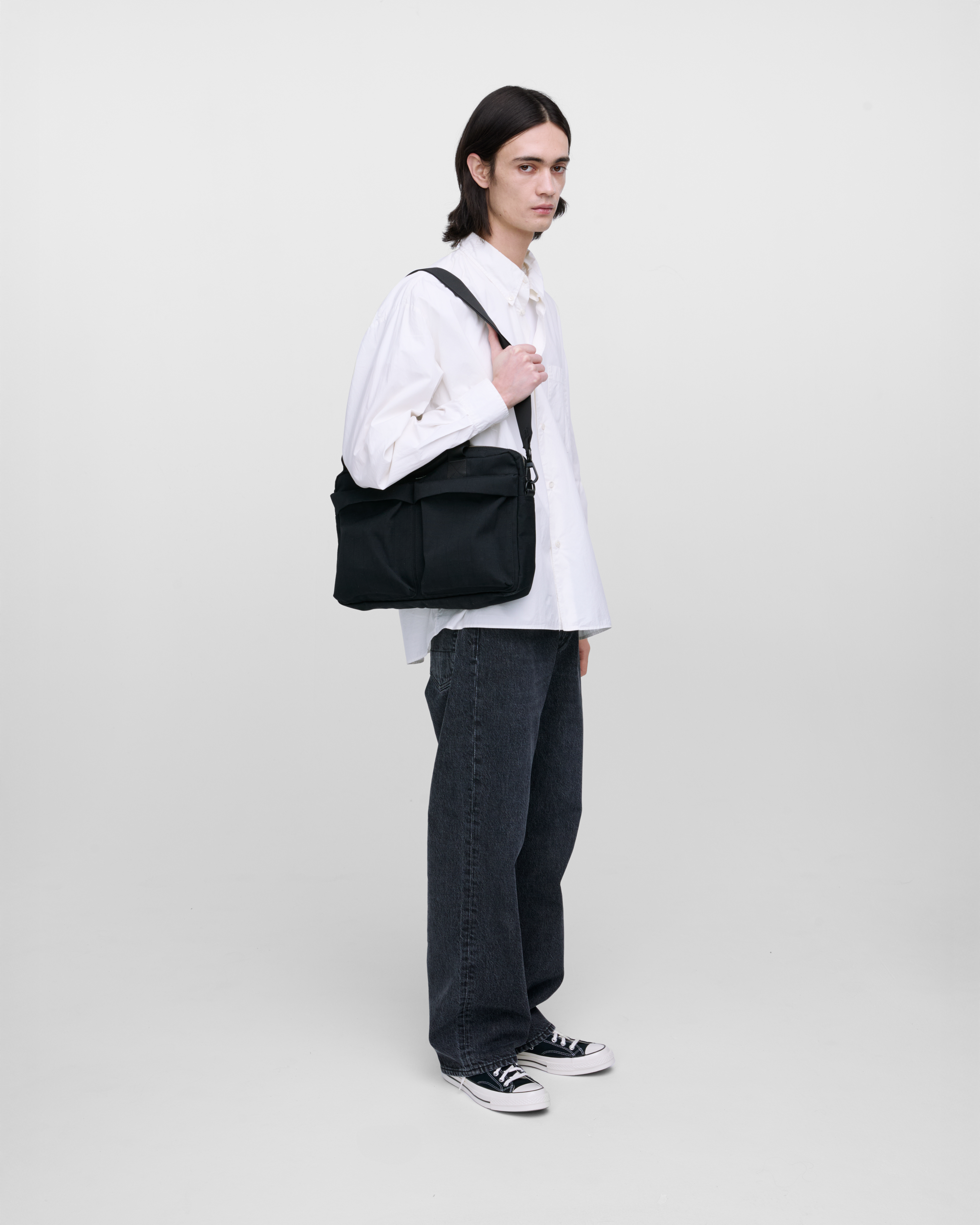 Male model wearing Sandqvist Everyday Briefcase, black. Side view, wearing the bag on one shoulder.