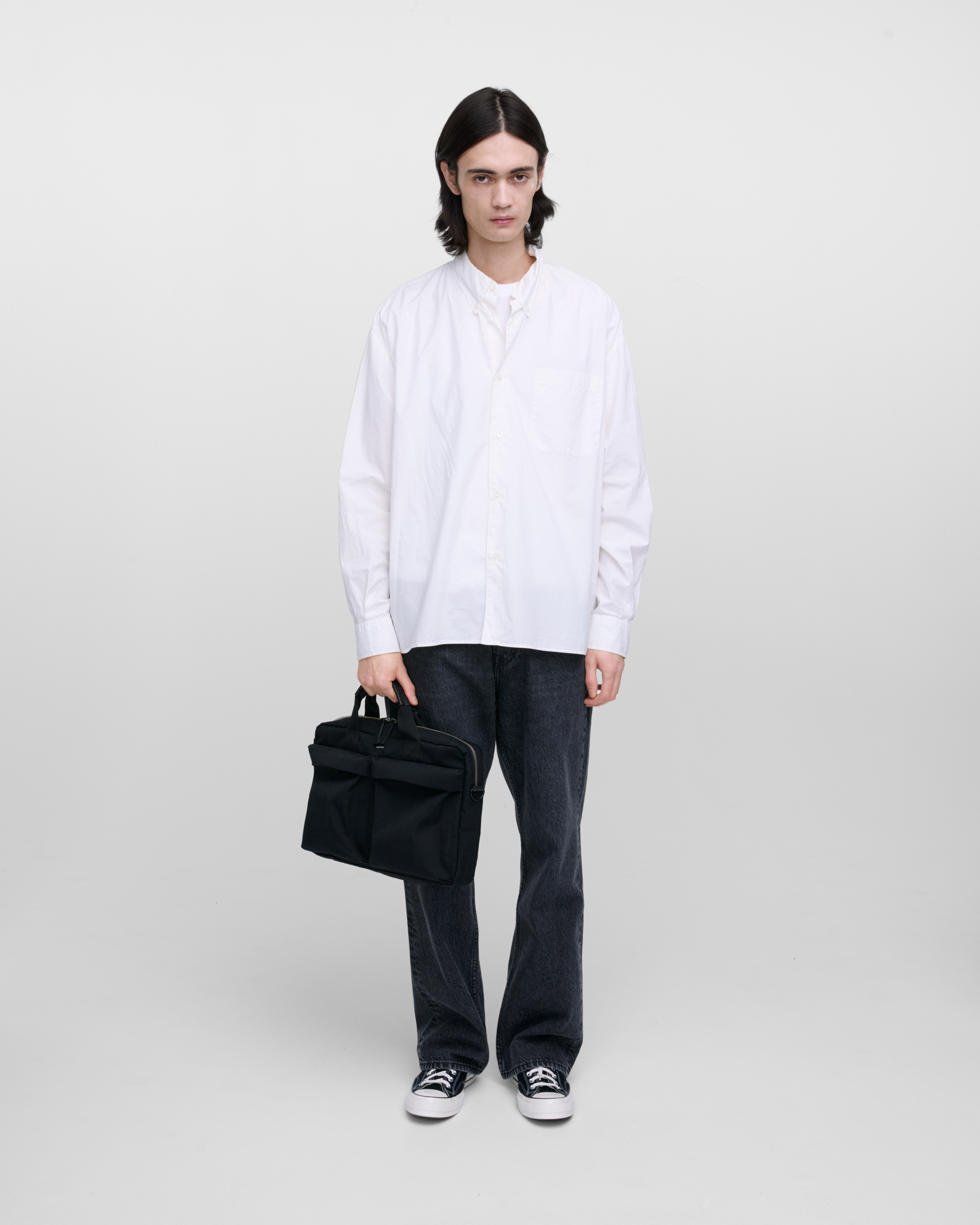 Male model holding Sandqvist Everyday Briefcase, black. Front view, holding the bag in one hand.