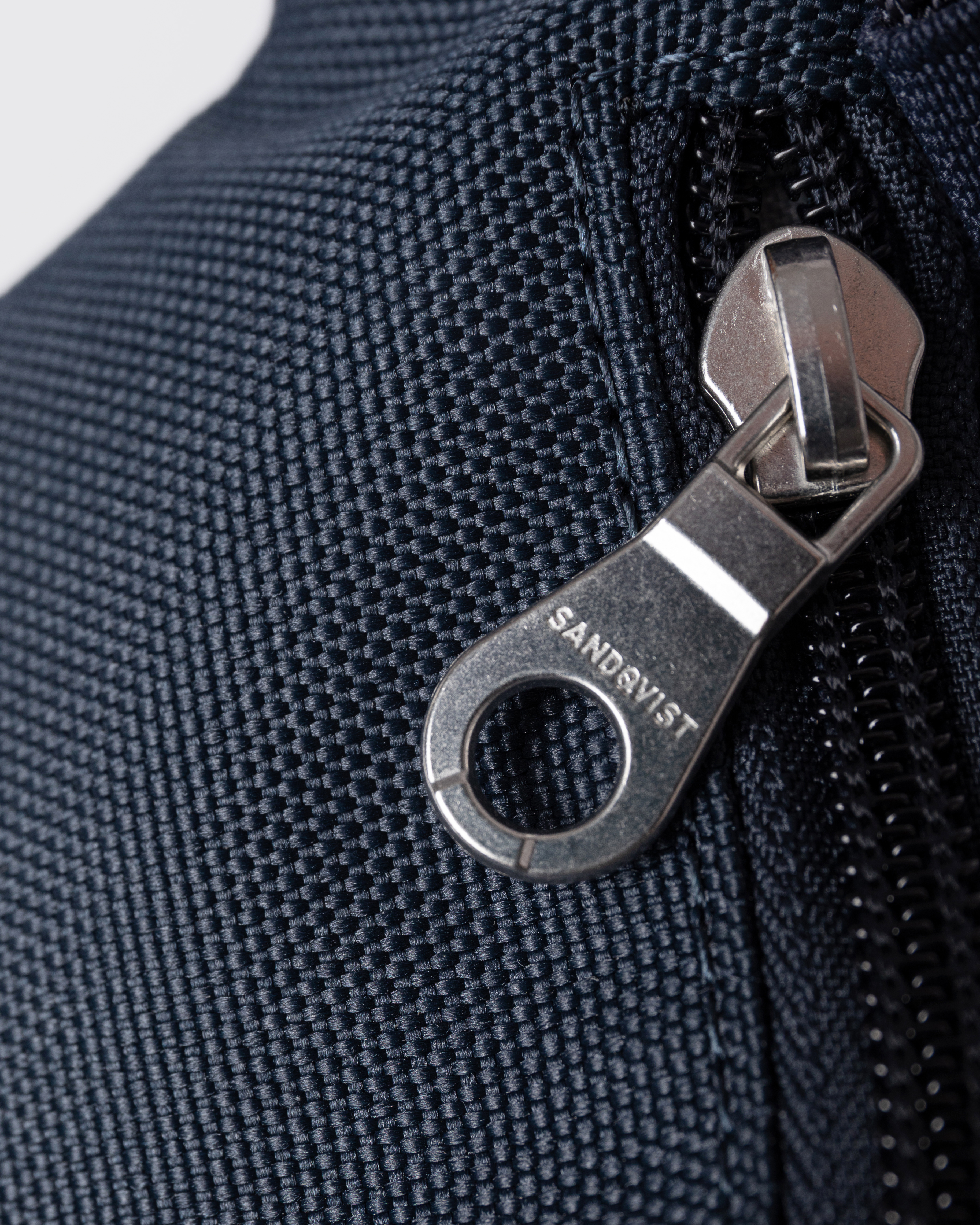 Sandqvist Ground Crossbody Bag, blue. Close-up of zipper-puller.