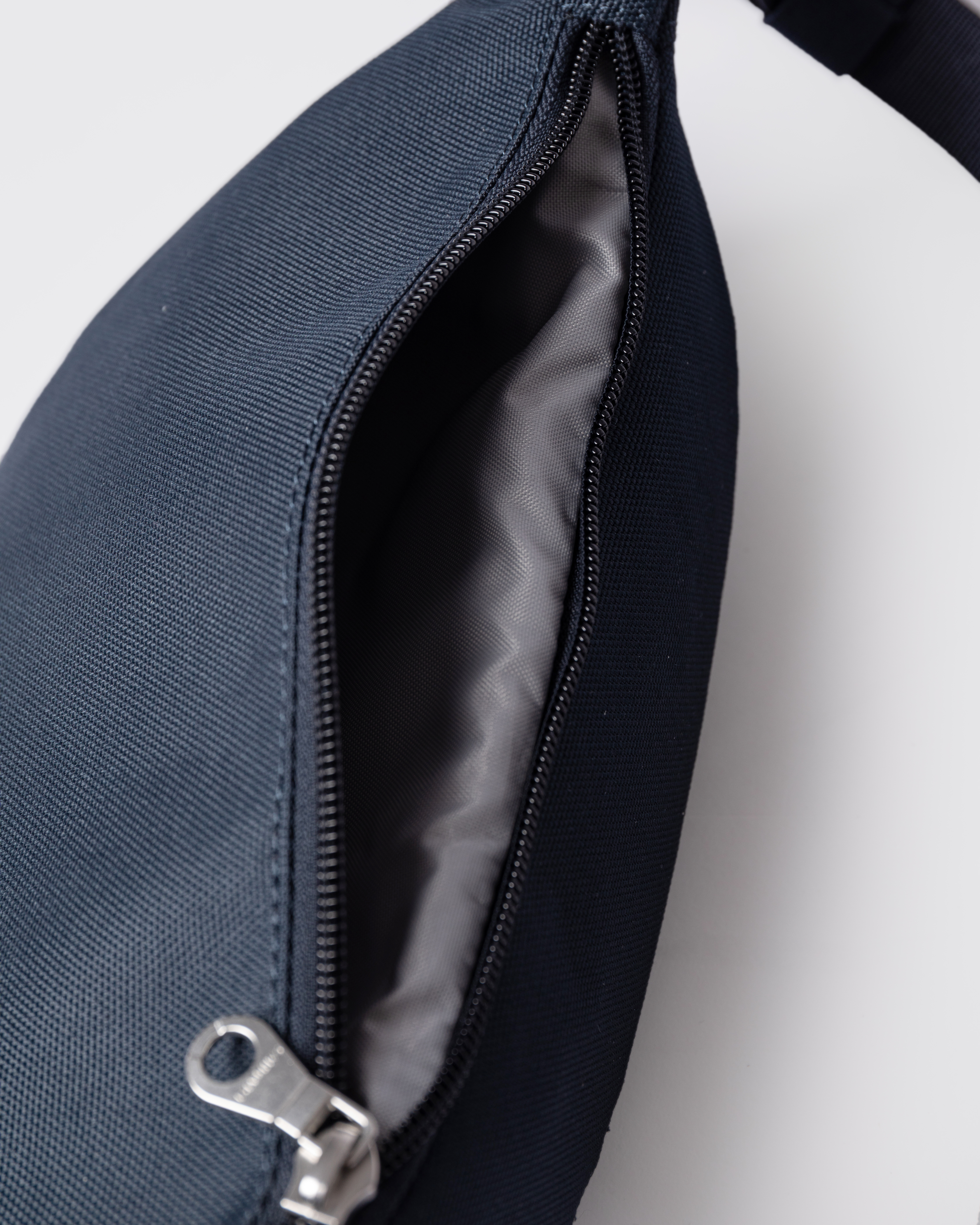 Sandqvist Ground Crossbody Bag, blue. Close-up of the open zipper.