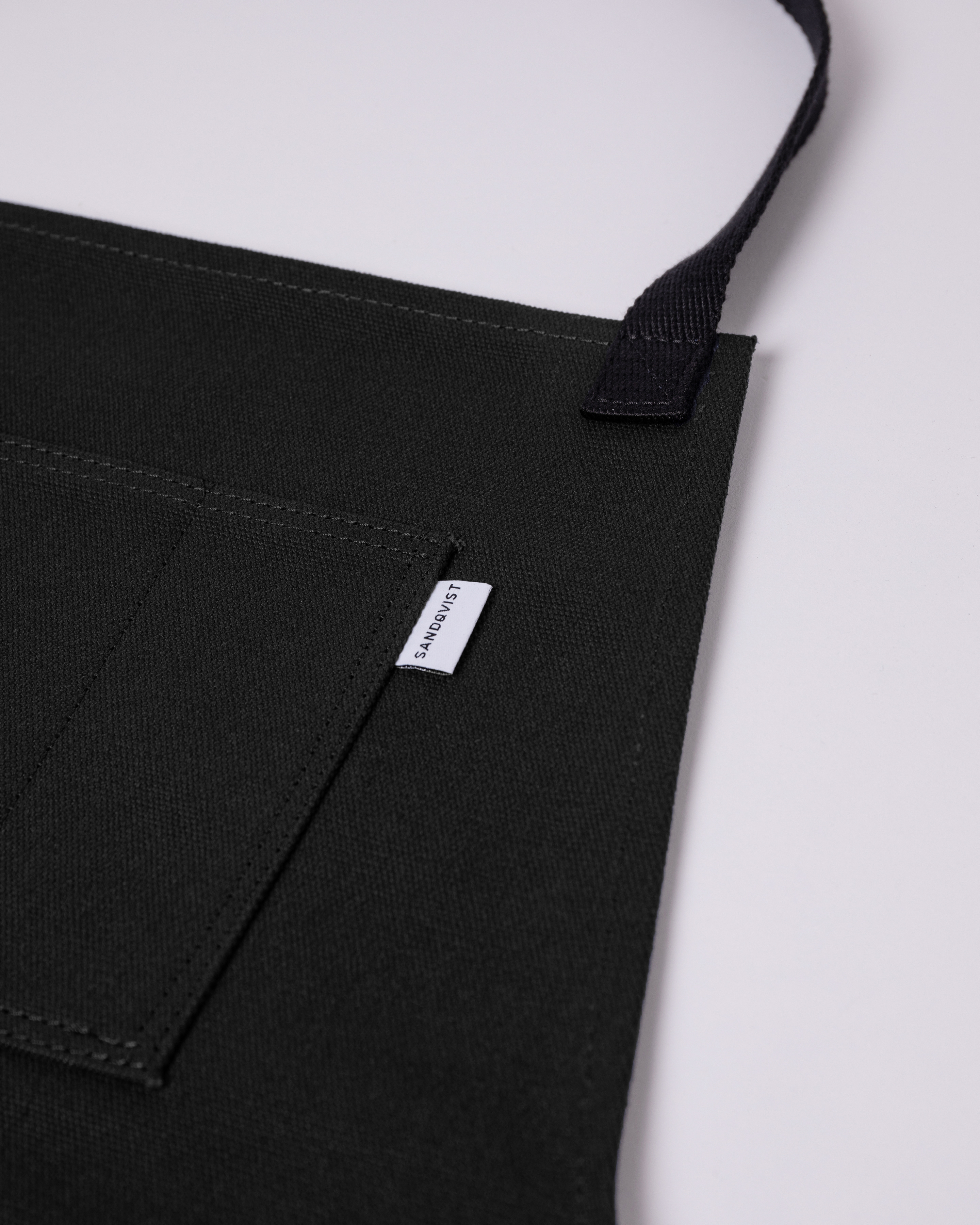Close up view showing chest pocket on Sandqvist Apron in Black. 