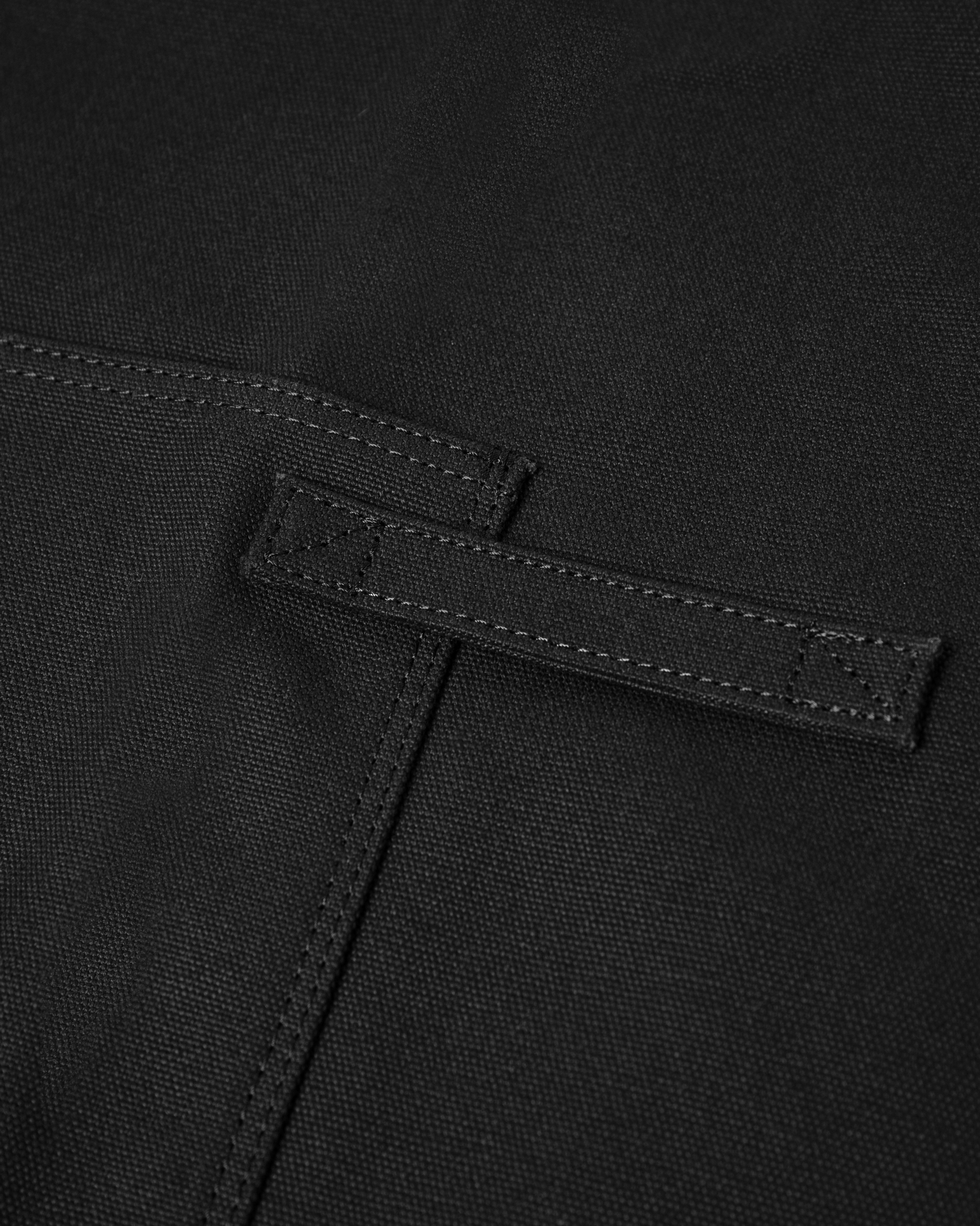 Close up view showing chest pocket on Sandqvist Apron in Black. 