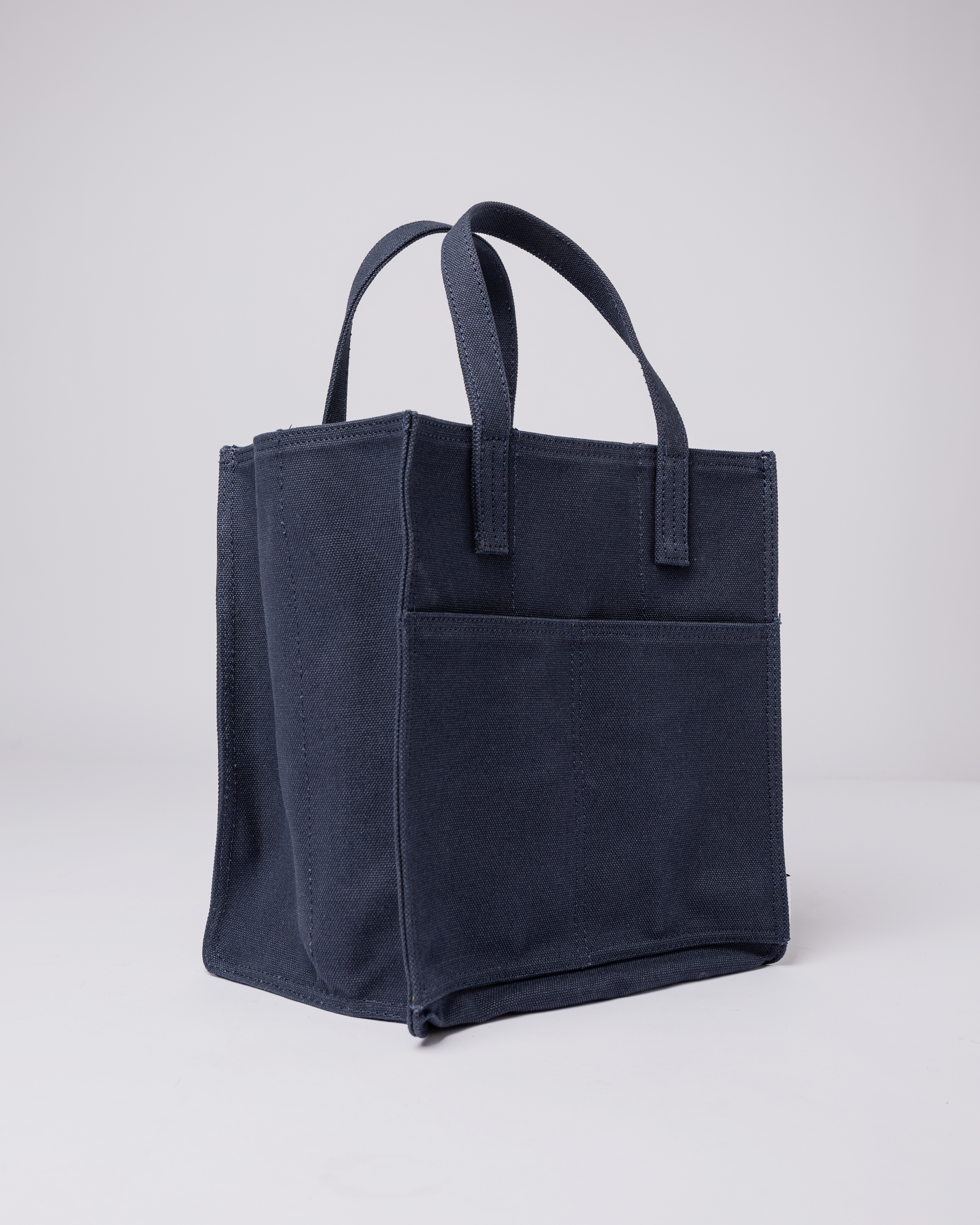 Sac à bouteille. Sandqvist Bottle Bag en bleu marine, vue latérale avec poignées supérieures et poche avant.