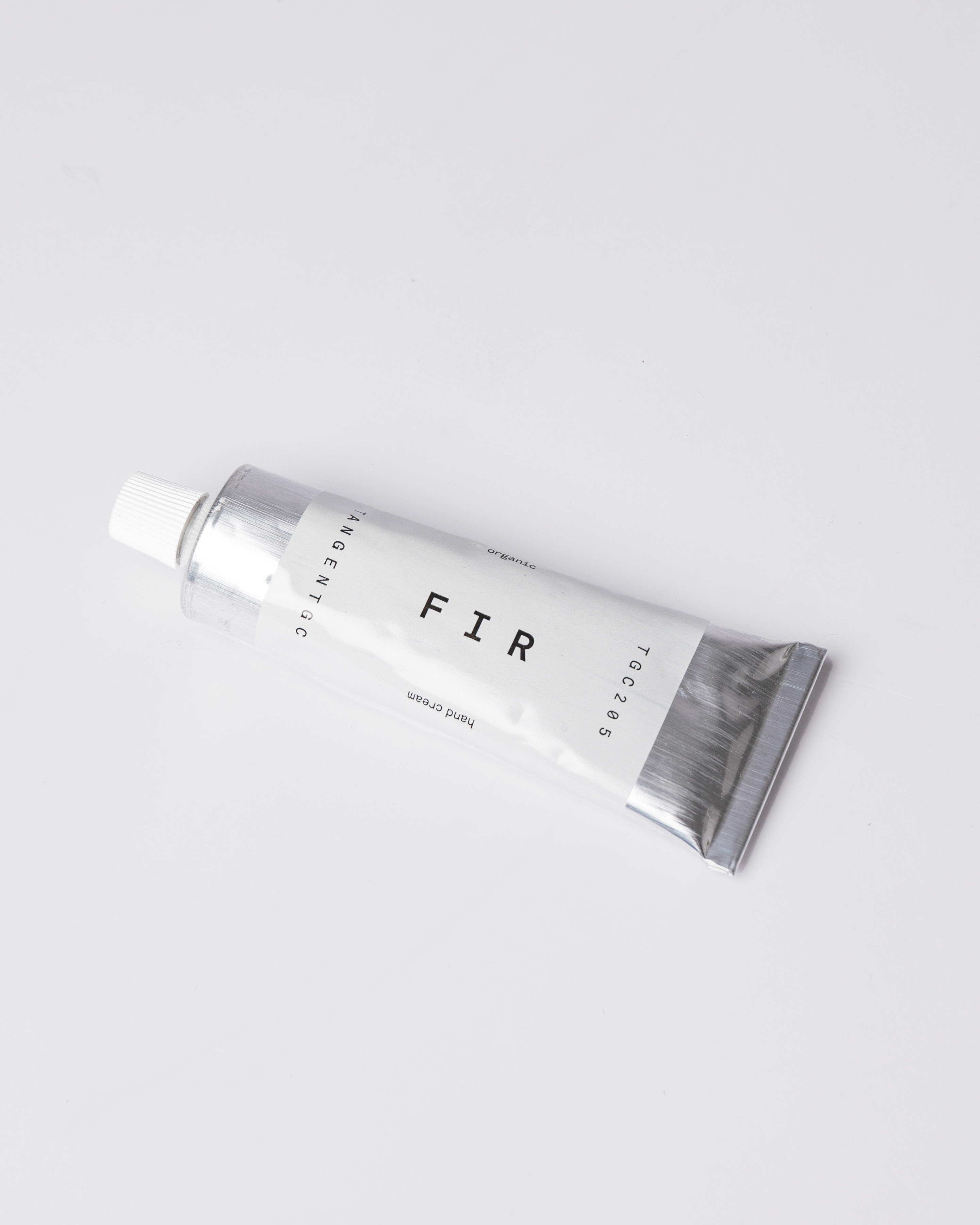 Hand cream in silver tube with white lid. Top view showing Sandqvist Fir Hand Cream laying on flat surface.