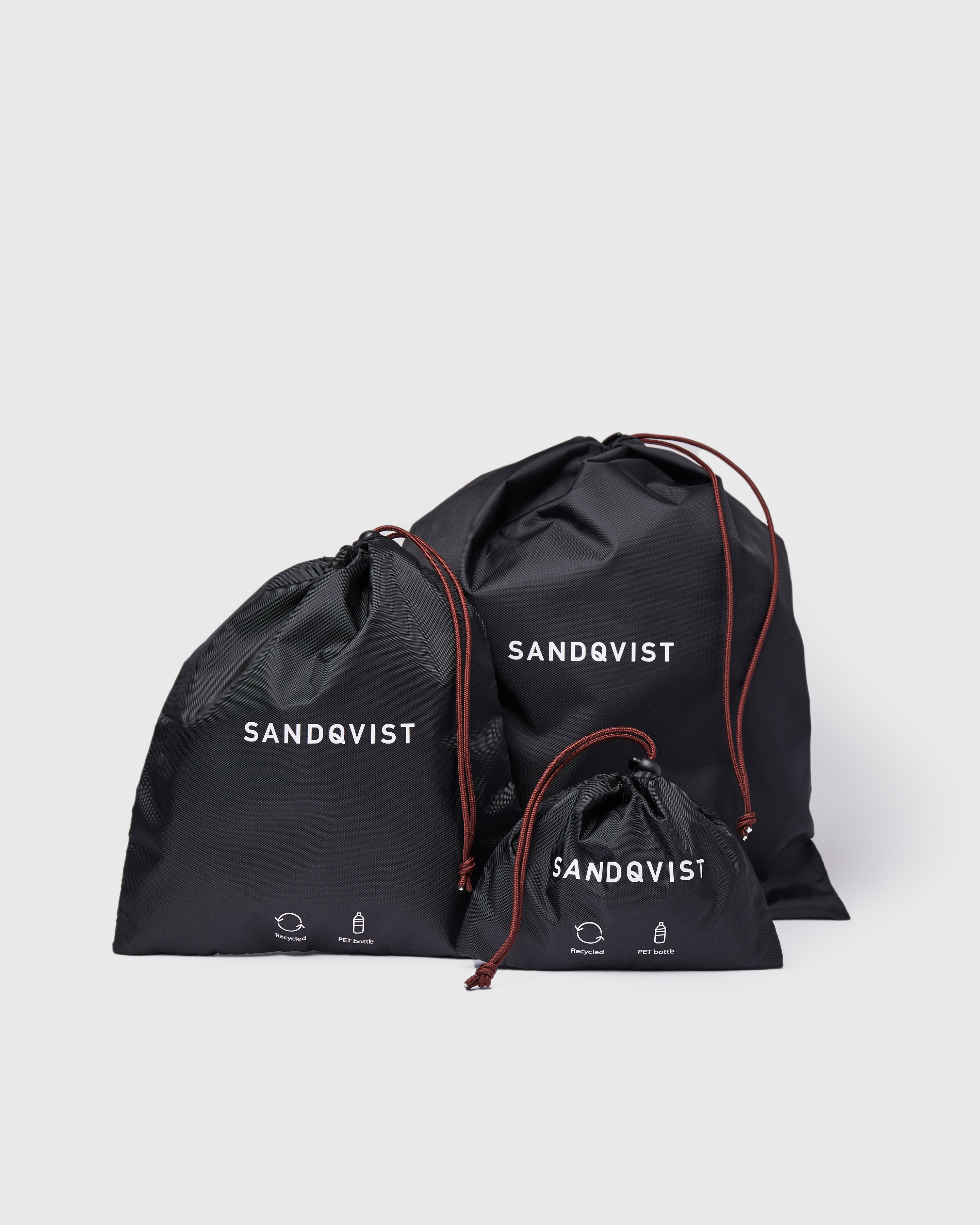 Three Pack bags in black, front view with three Sandqvist ITEMS Pack Bags in different sizes with drawstring closure.