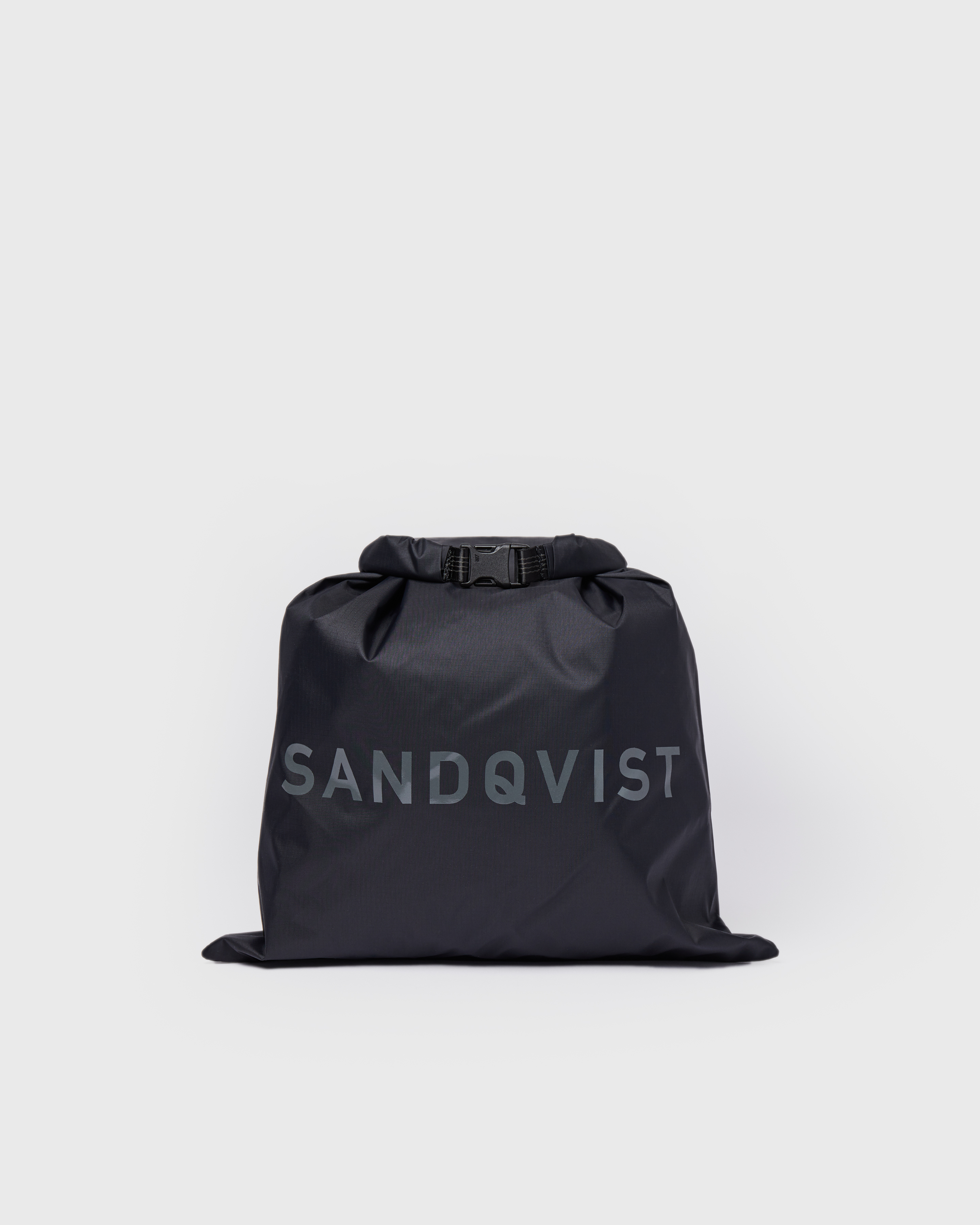 Fully packed dry bag in black with a large Sandqvist logotype with rolltop closure and buckle. Showing Sandqvist ITEMS Dry bag. 