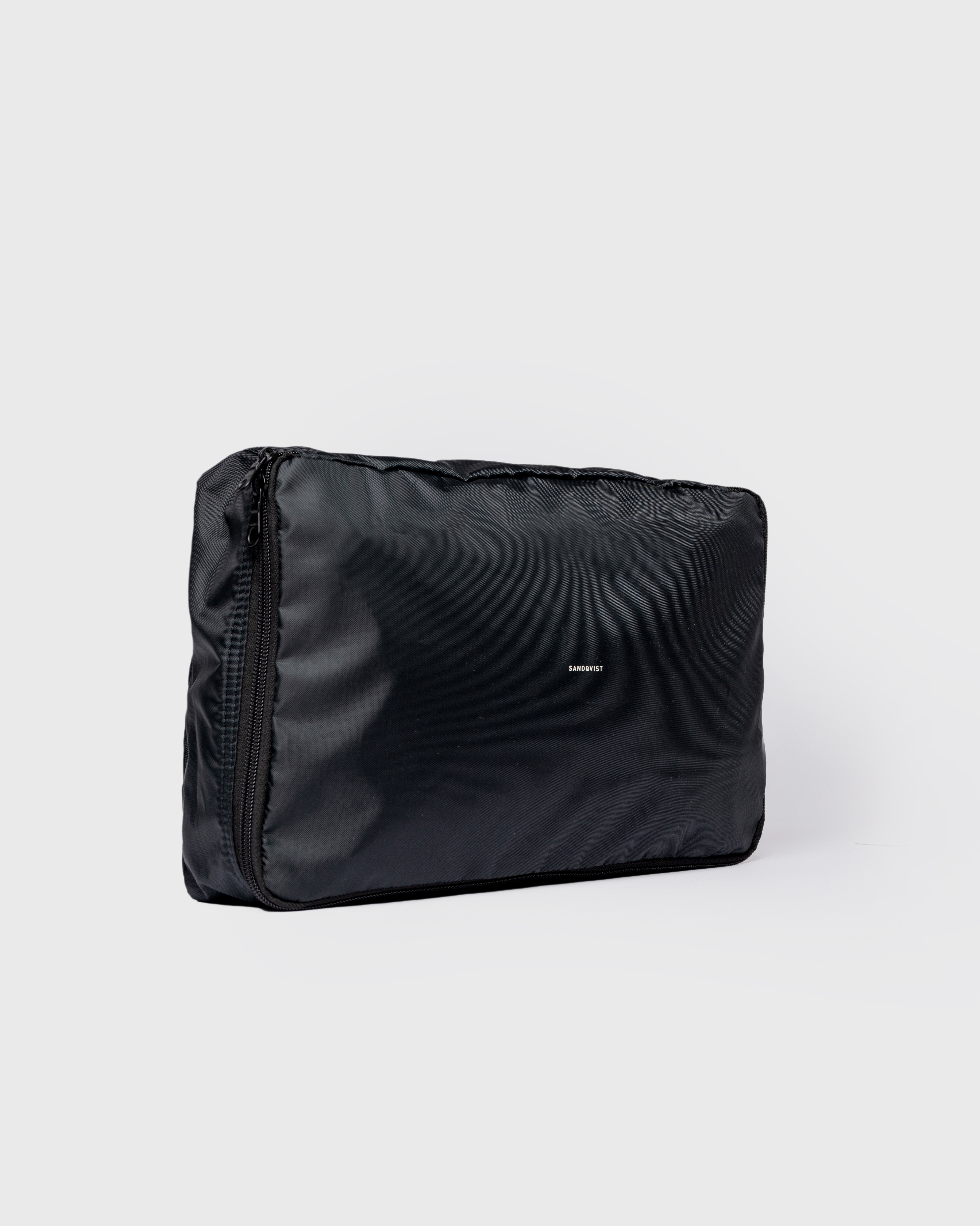 Black packing Cube with Sandqvist Logotype. Side view showing Sandqvist ITEMS Packing Cube M in black with zipper closure.