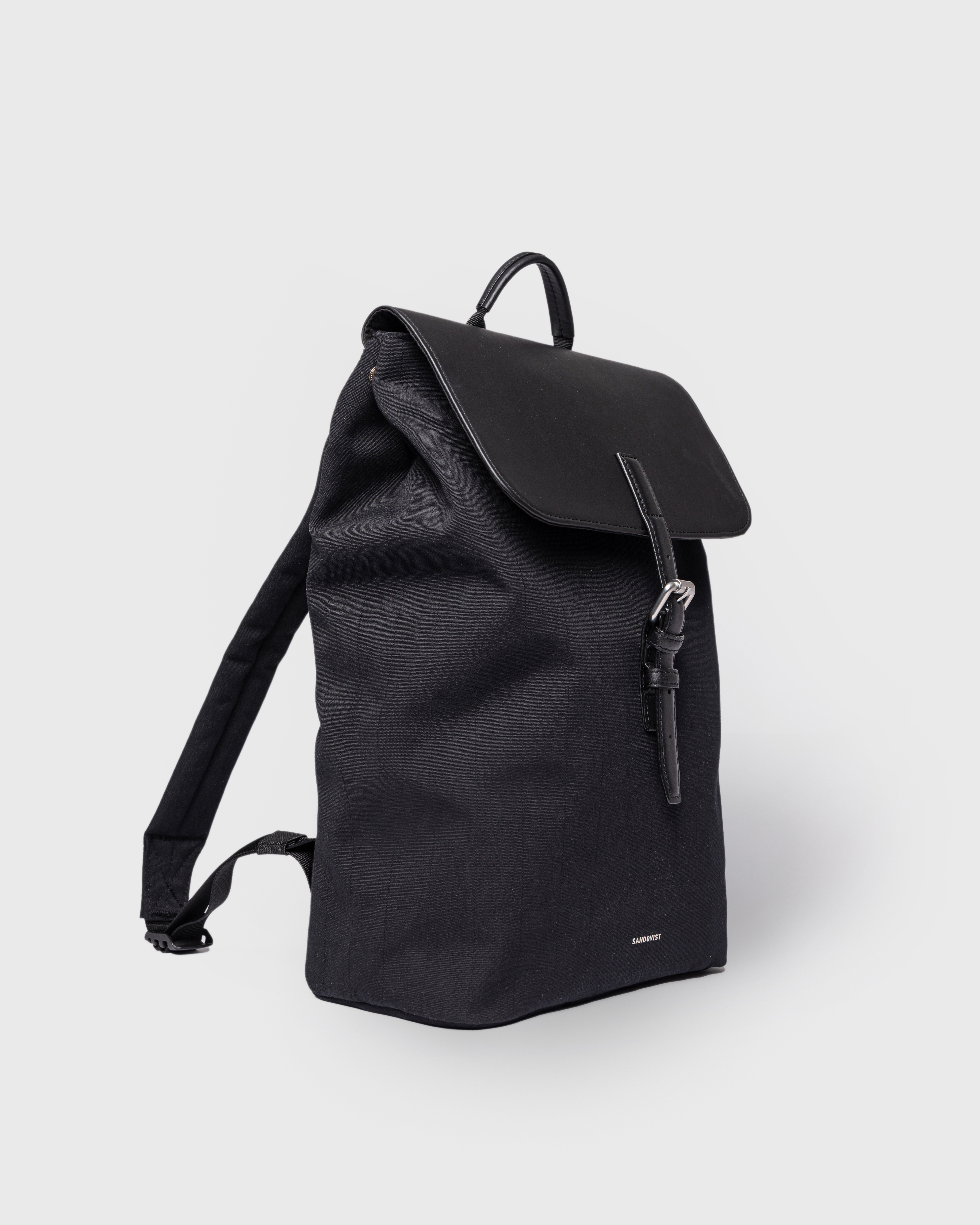 Sandqvist Everyday Lid Backpack M, black. Side view, lid with buckle, handle and shoulder strap.