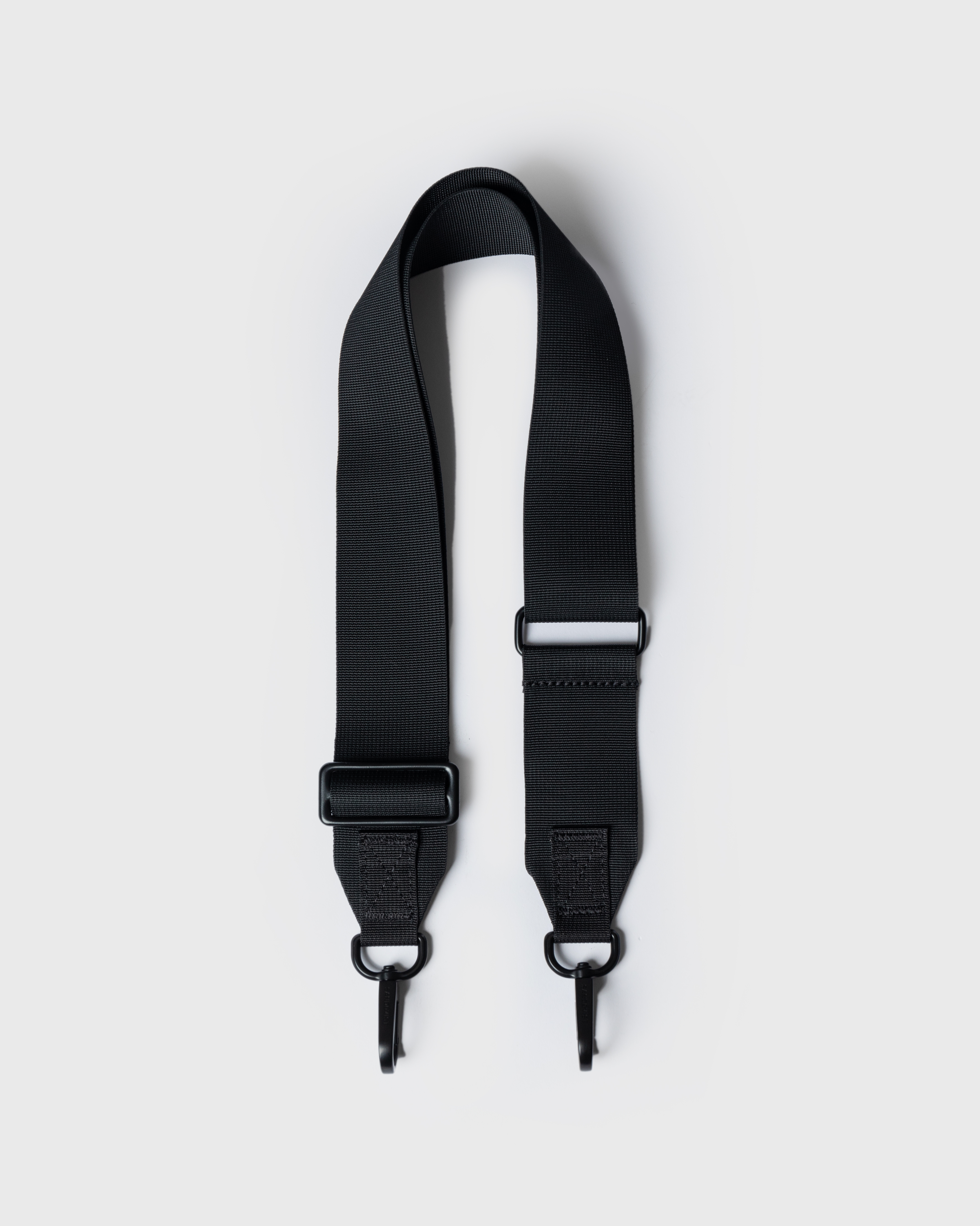Black Shoulder strap. Top view showing Sandqvist ITEMS Shoulder Strap with black metal trims and buckles.  