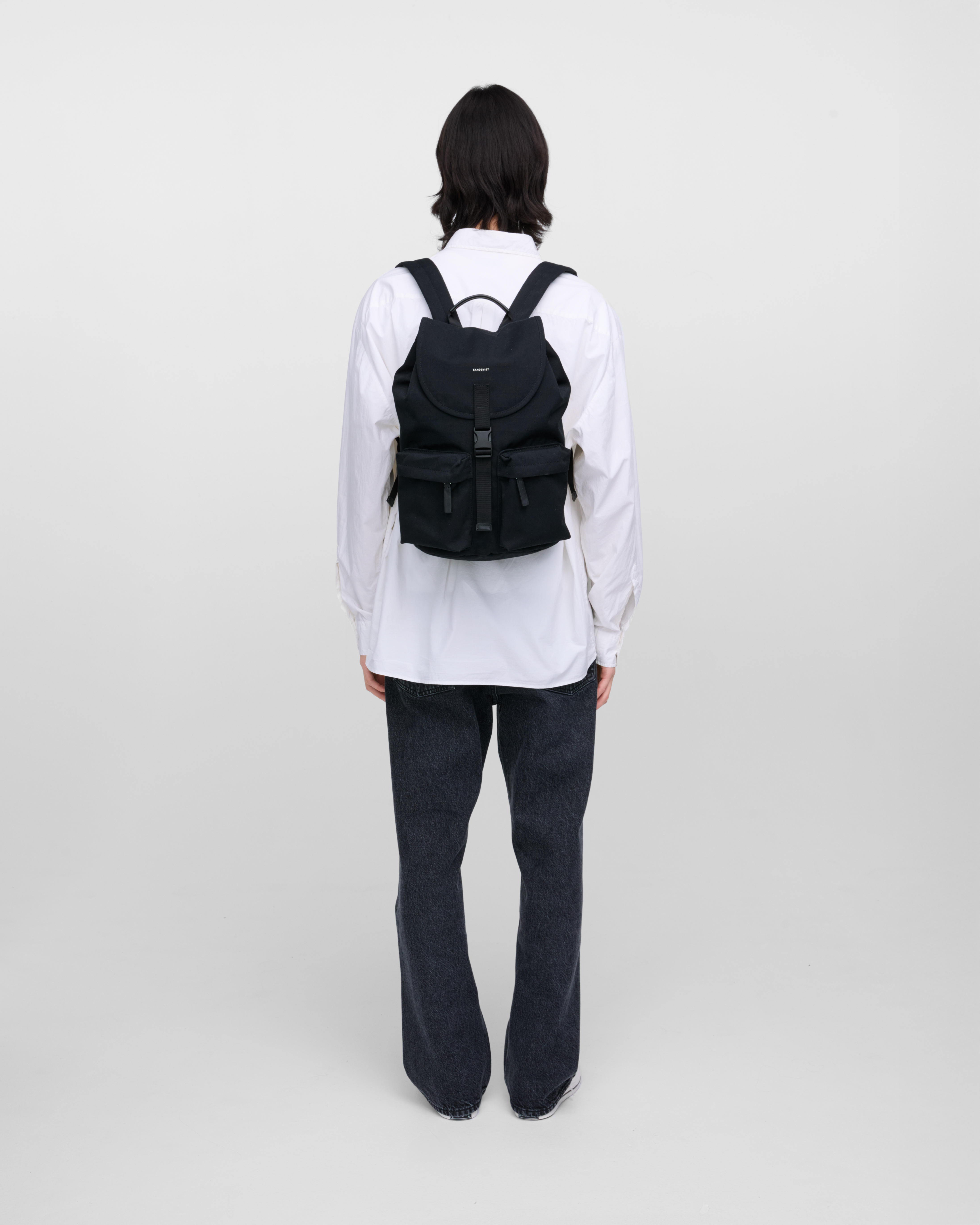 Male model wearing Sandqvist Everyday Rucksack, black. Back view, wearing the bag on the back.