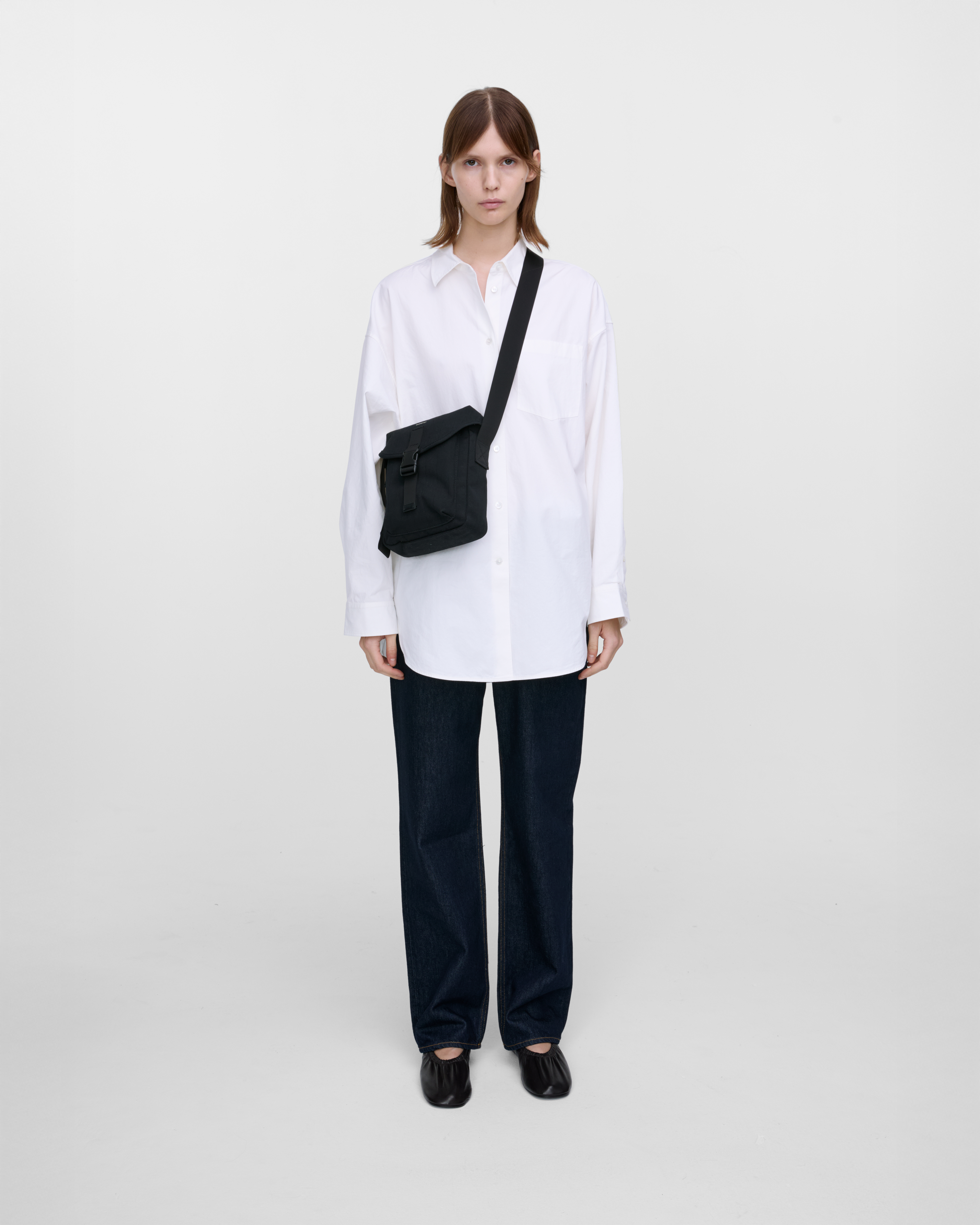 Female model wearing Sandqvist Everyday crossbody bag, black. Front view, wearing the bag on one shoulder crossbody, with the bag in the front.