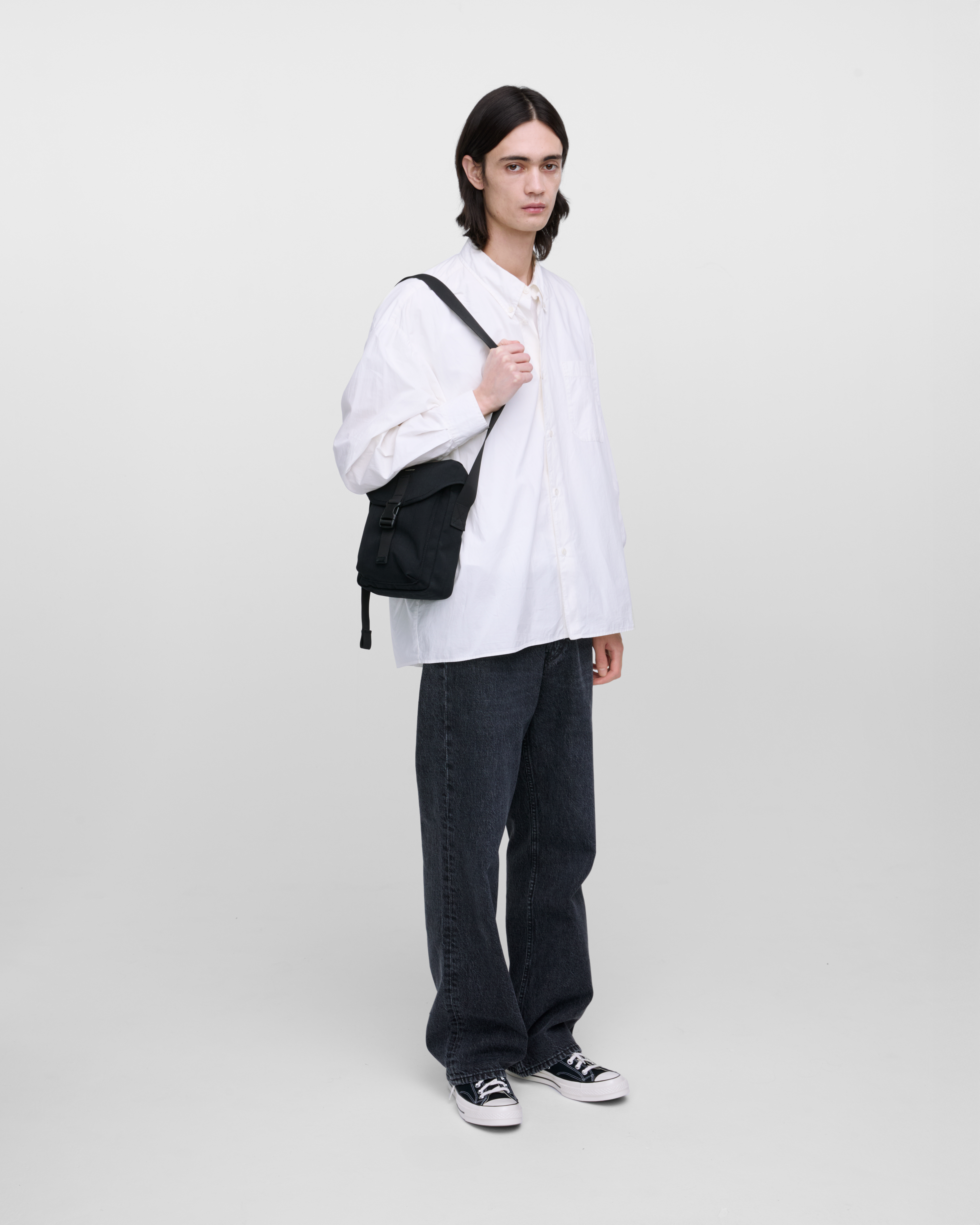 Male model wearing Sandqvist Everyday crossbody bag, black. Front view, wearing the bag on one shoulder.