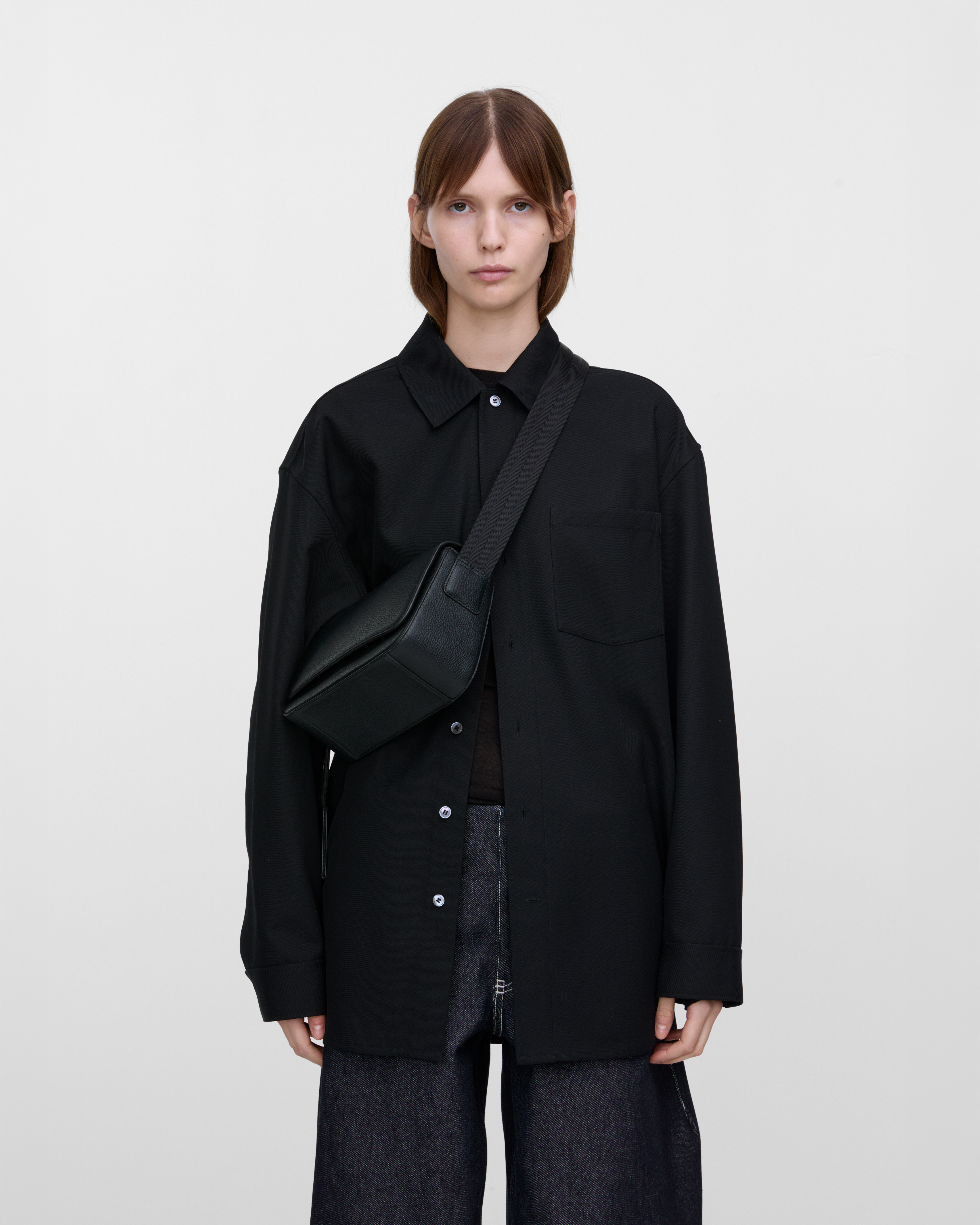 Female model wearing Sandqvist Agile Crossbody Bag, black. Front view, wearing the bag on one shoulder crossbody.