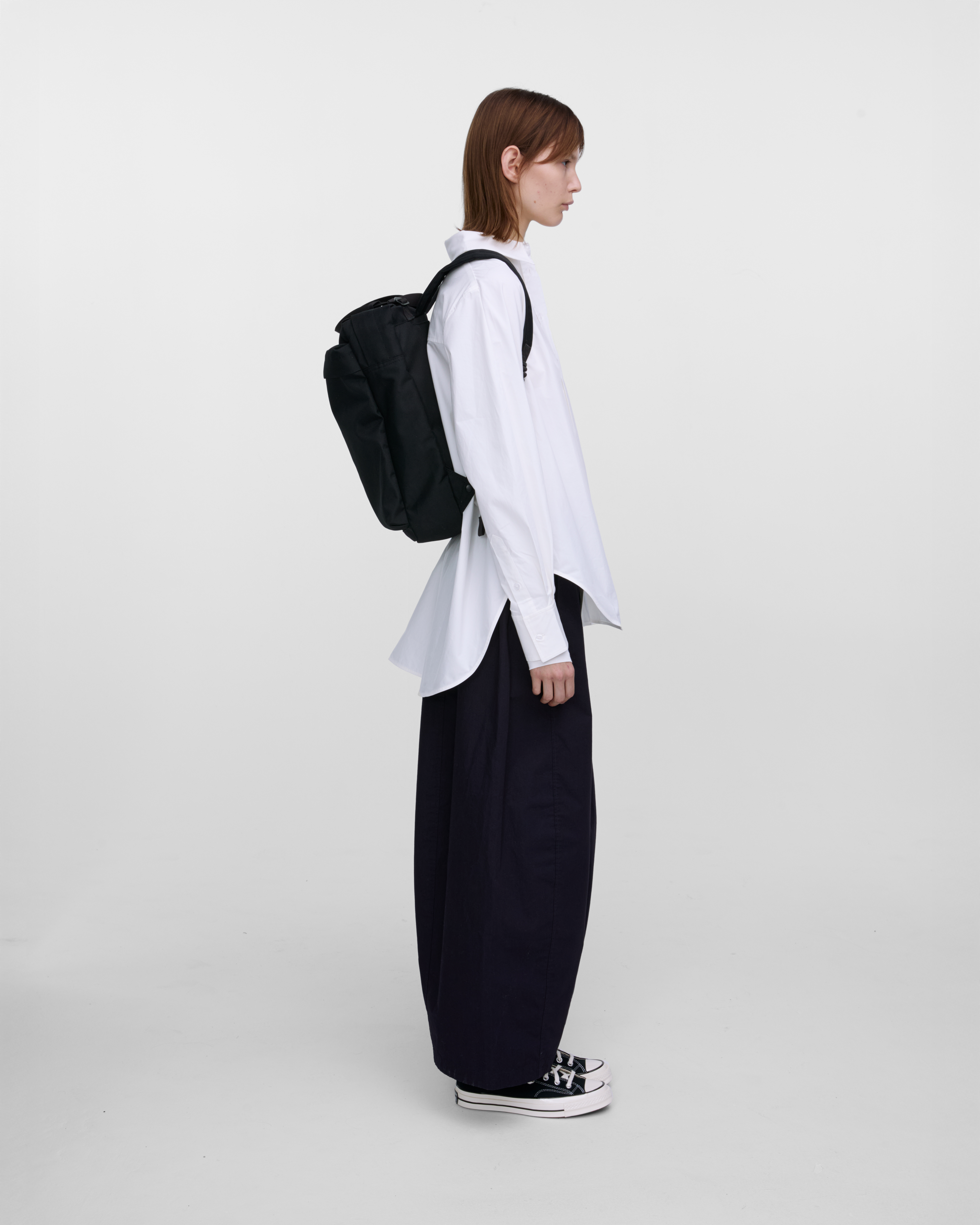 Female model wearing Sandqvist Go 2-way Tote Bag, black. Side view, wearing the bag on the back.