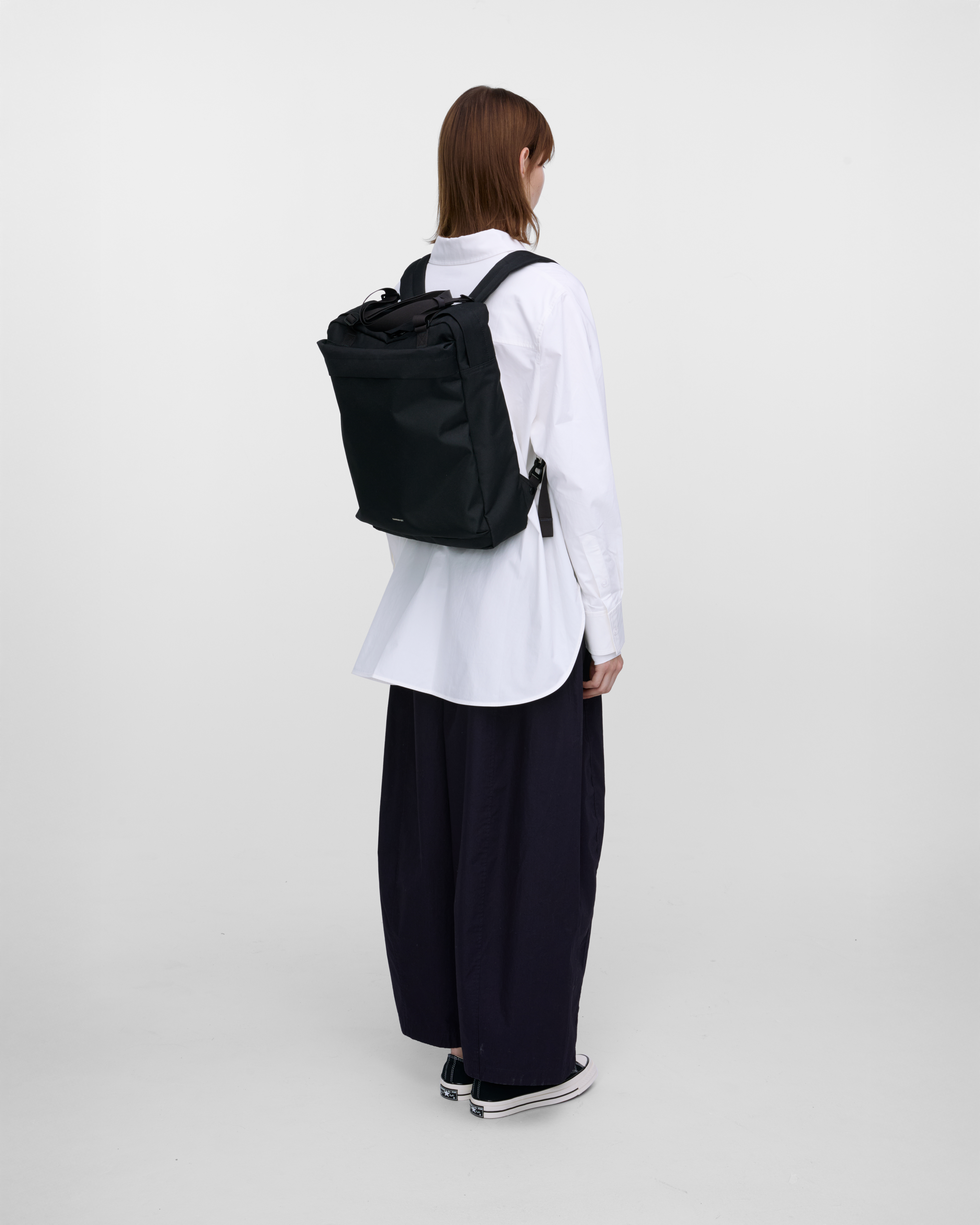 Female model wearing Sandqvist Go 2-way Tote Bag, black. Back view, wearing the bag on the back.