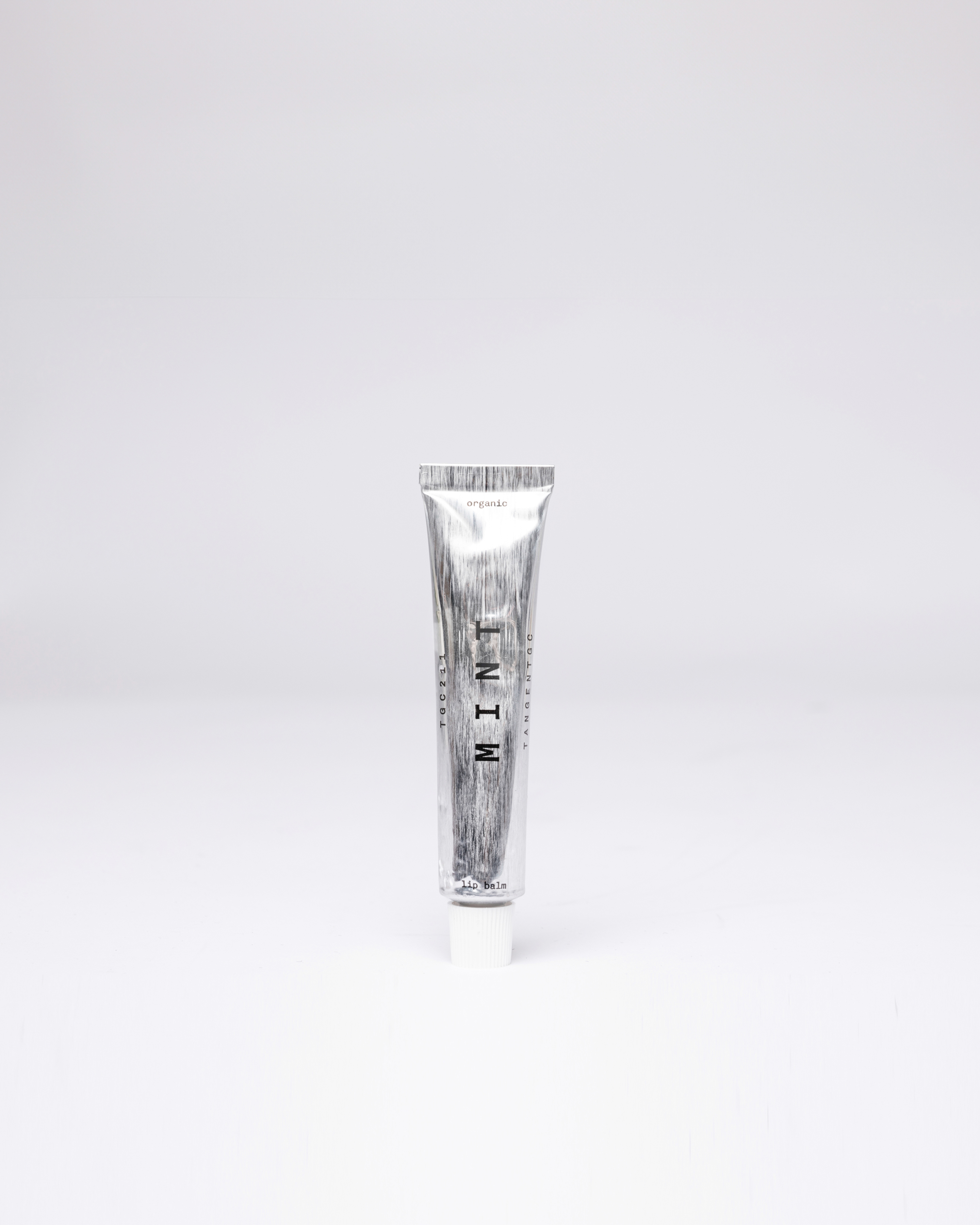 Lip balm in silver tube with white lid. Front view showing Sandqvist Mint lip balm.