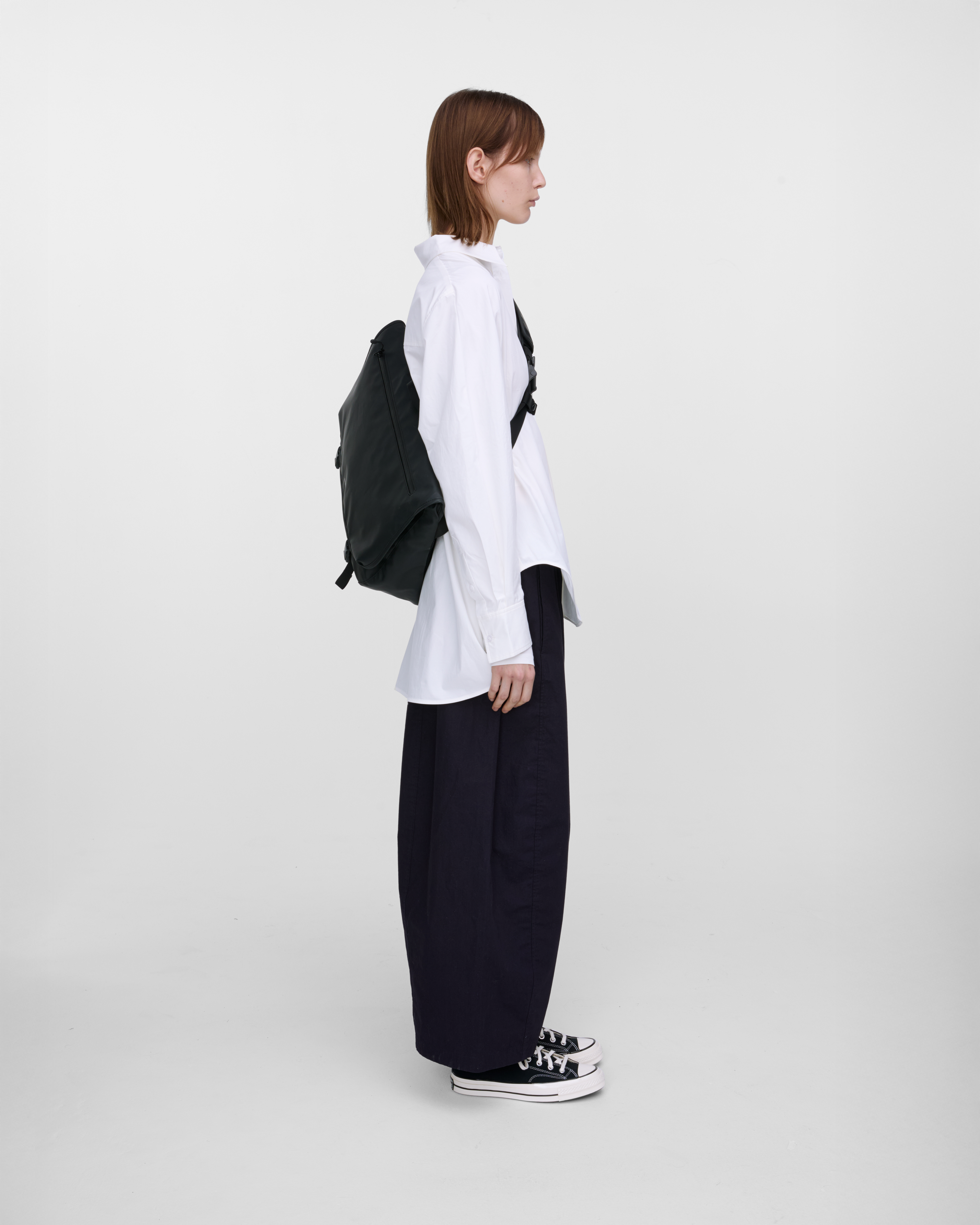Female model carrying Sandqvist STREAM Messenger Bag in Black on the left shoulder. Right side view showing fit and size.