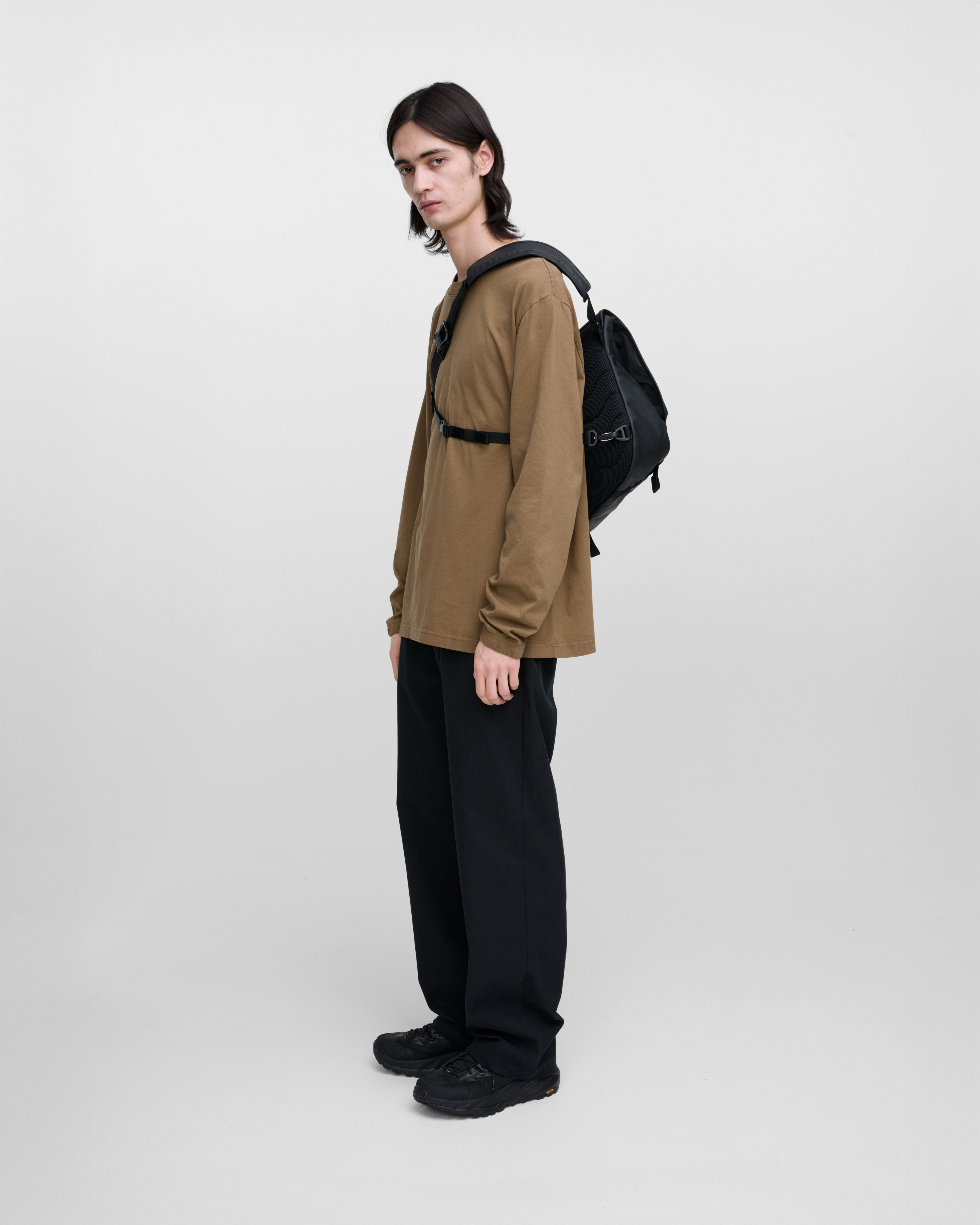 Male model carrying Sandqvist STREAM Messenger Bag in Black on the right shoulder. Left side view showing fit, size and placement of chest strap..