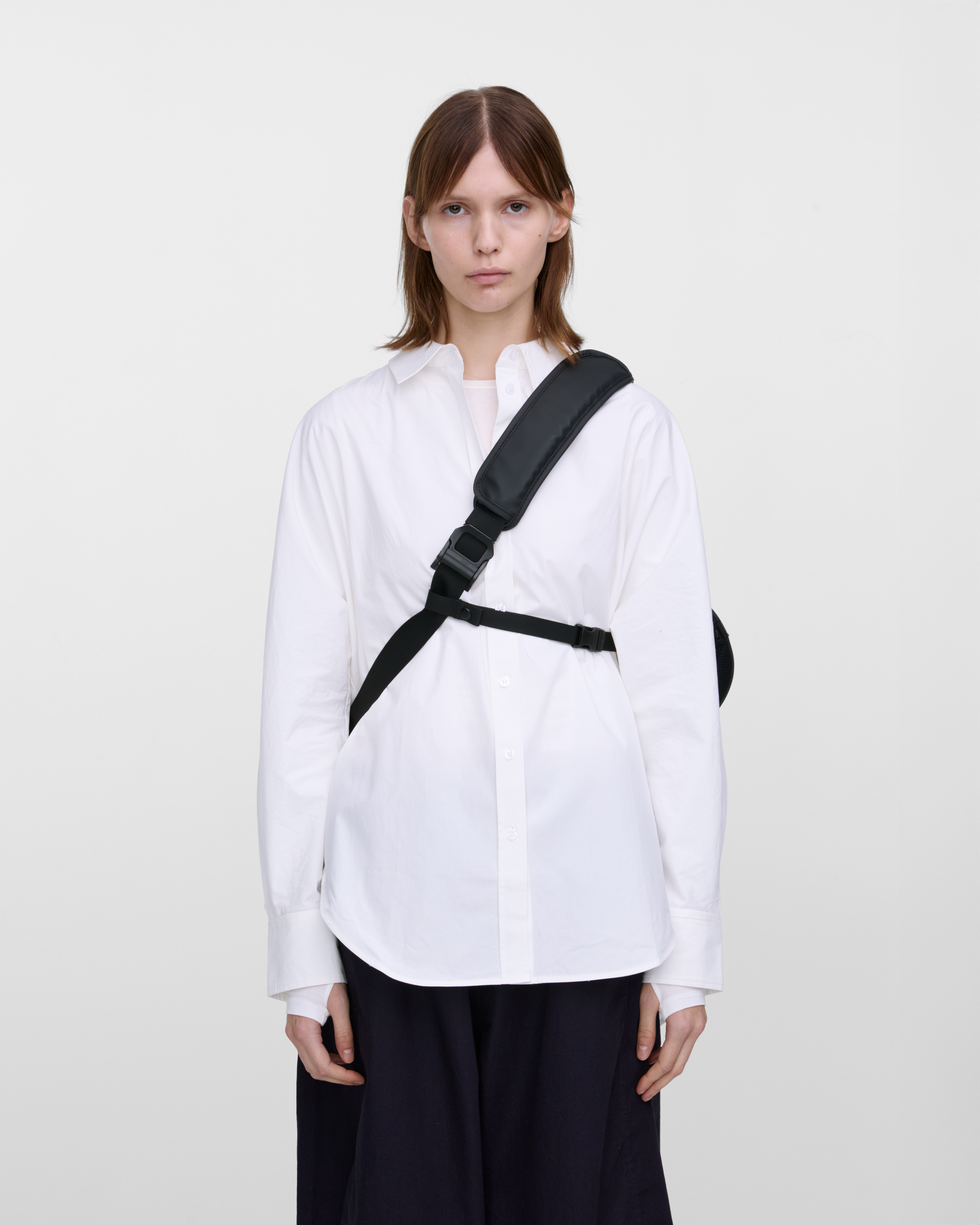 Female model carrying Sandqvist STREAM Messenger Bag in Black. Front view showing placement and fit of chest strap and shoulder strap.