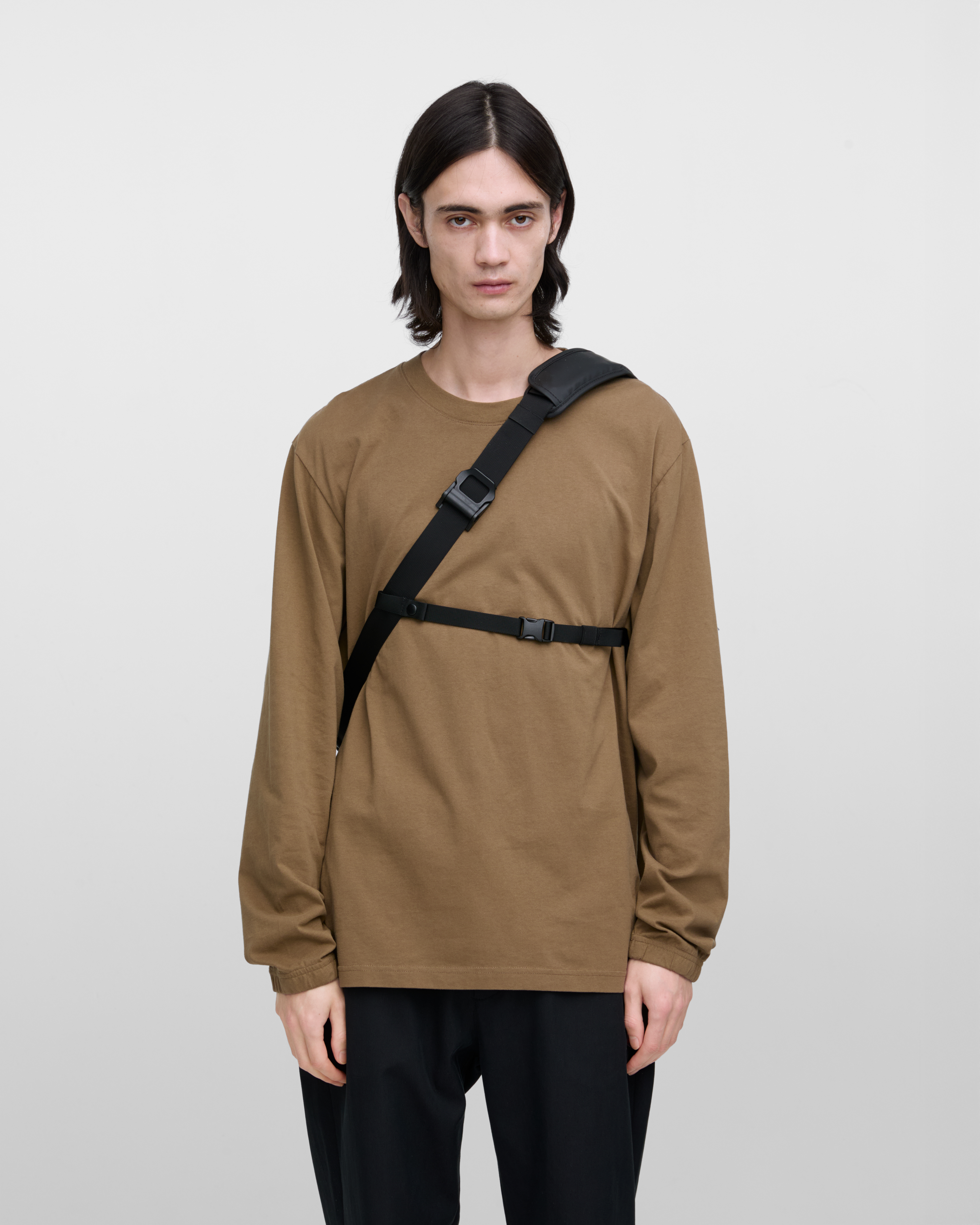 Male model carrying Sandqvist STREAM Messenger Bag in Black. Front view showing placement and fit of chest strap and shoulder strap.