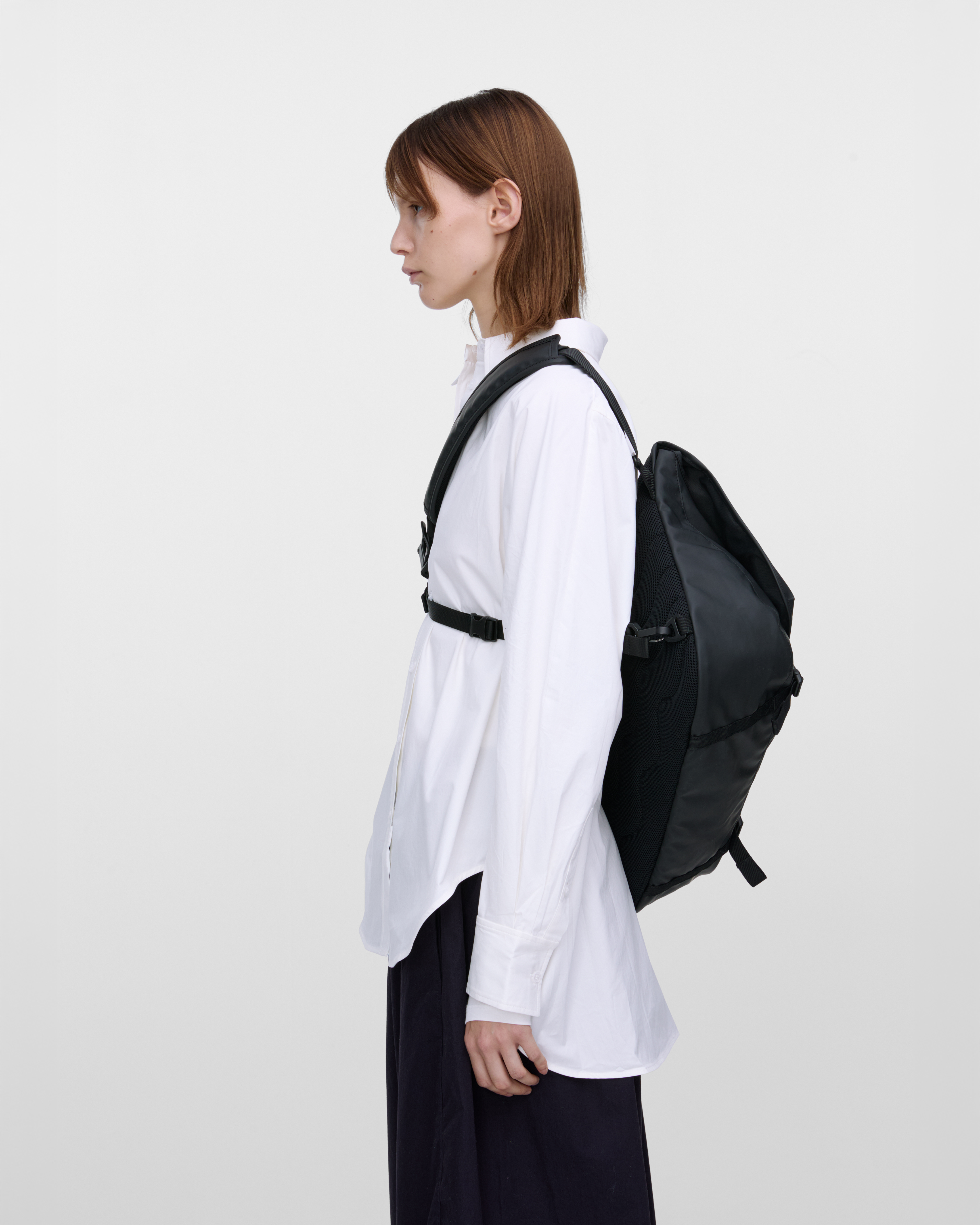 Female model carrying Sandqvist STREAM Messenger Bag in Black on the right shoulder. Left side view showing fit, size and placement of chest strap.