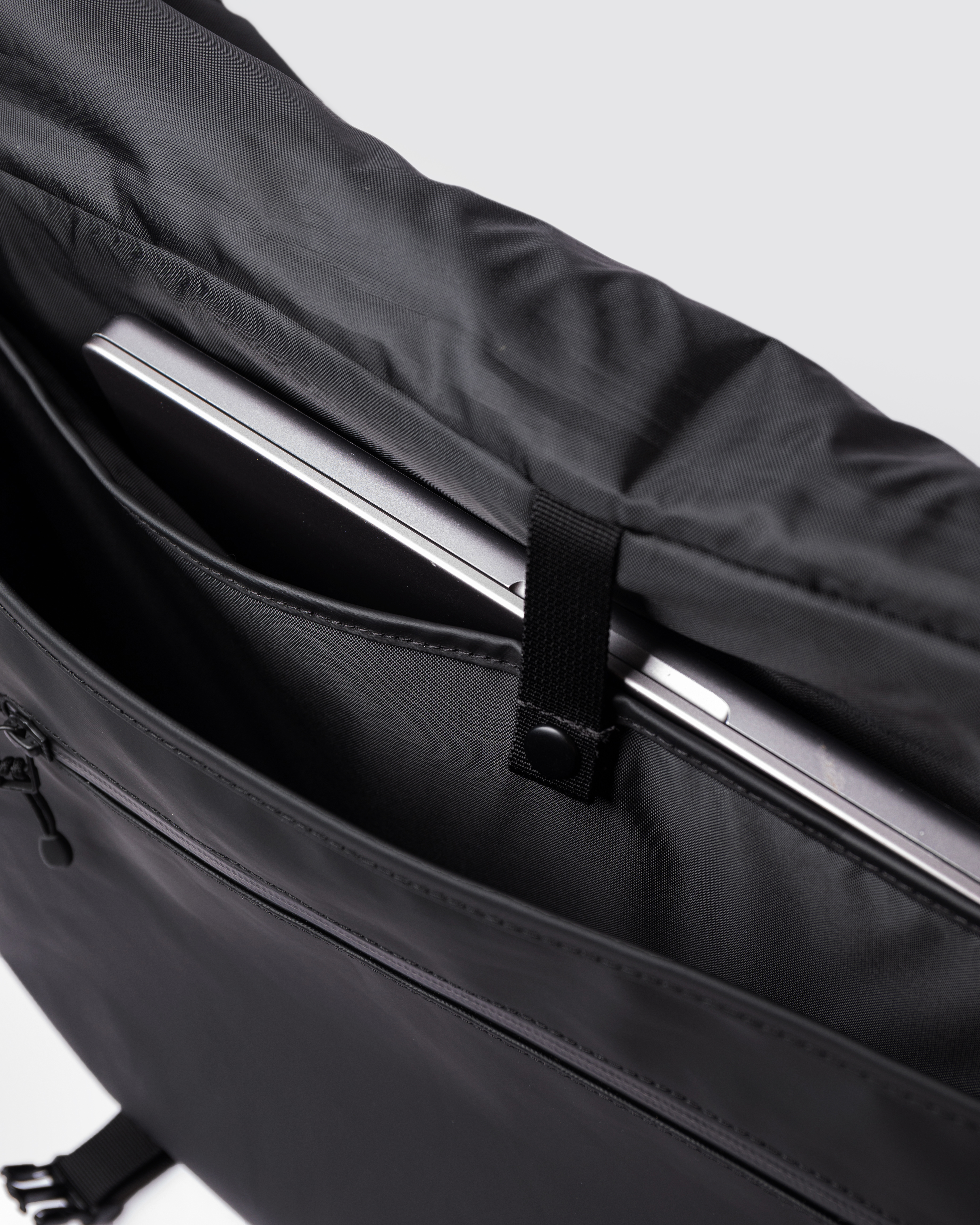 Sandqvist STREAM Messenger Bag in black with open lid and inside view with laptop compartment with bressbutton closure.