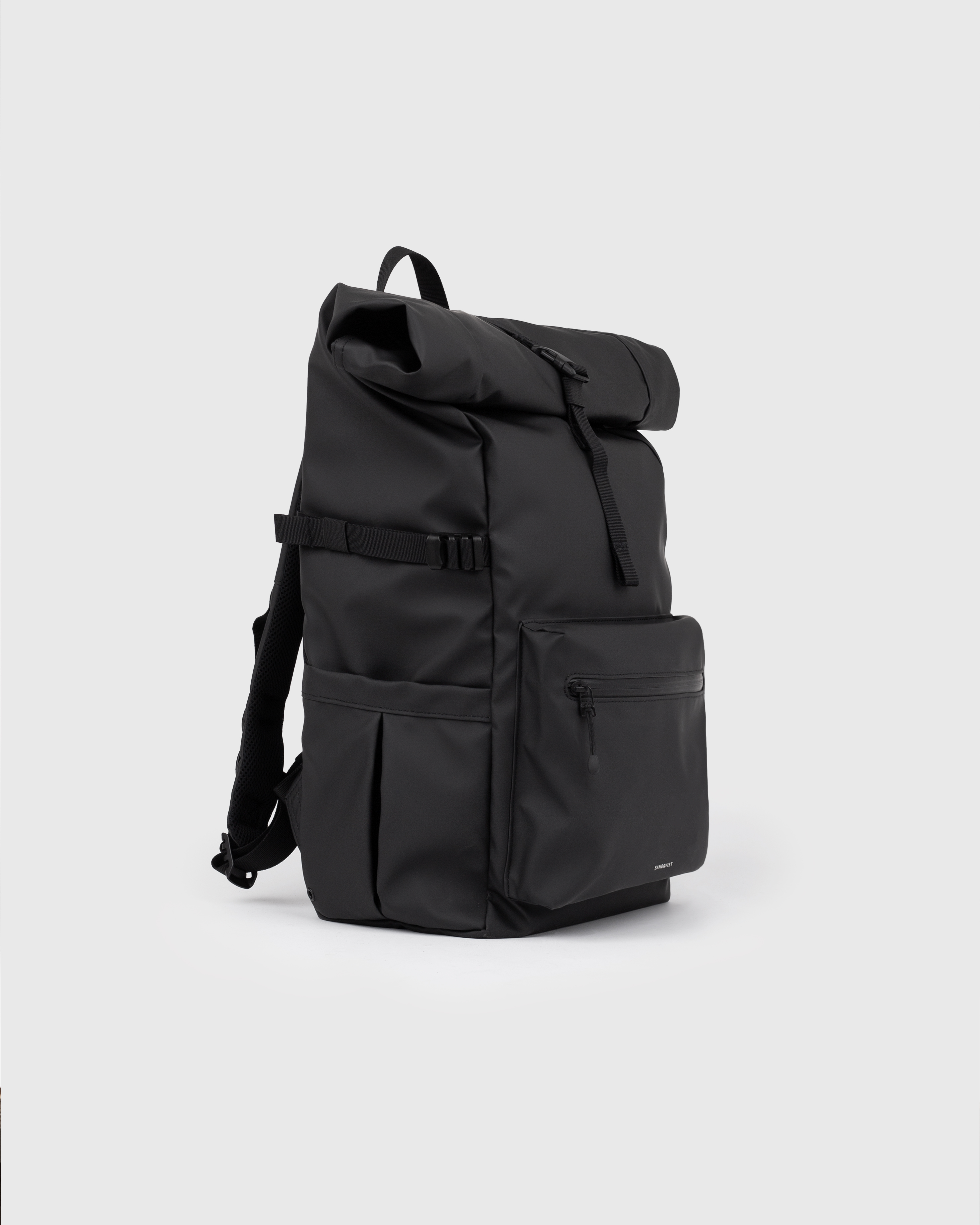 Backpack. Sandqvist STREAM Rolltop backpack L in black, side view with, top handle, zipper pocket at front, slip pocket, side strap and rolltop closure.