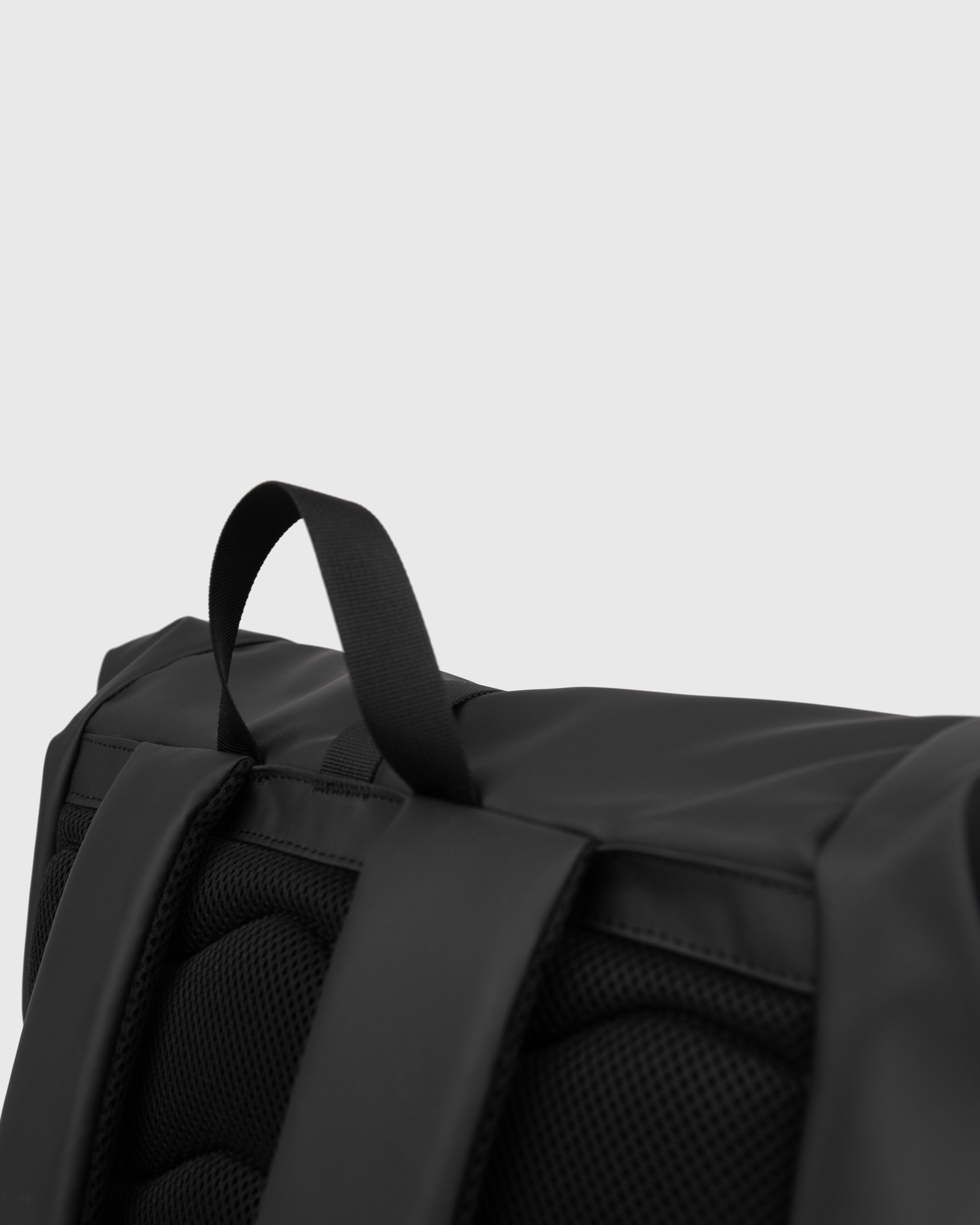 Sandqvist STREAM Rolltop Backpack L in black, close up view showing top handle and shoulder straps.