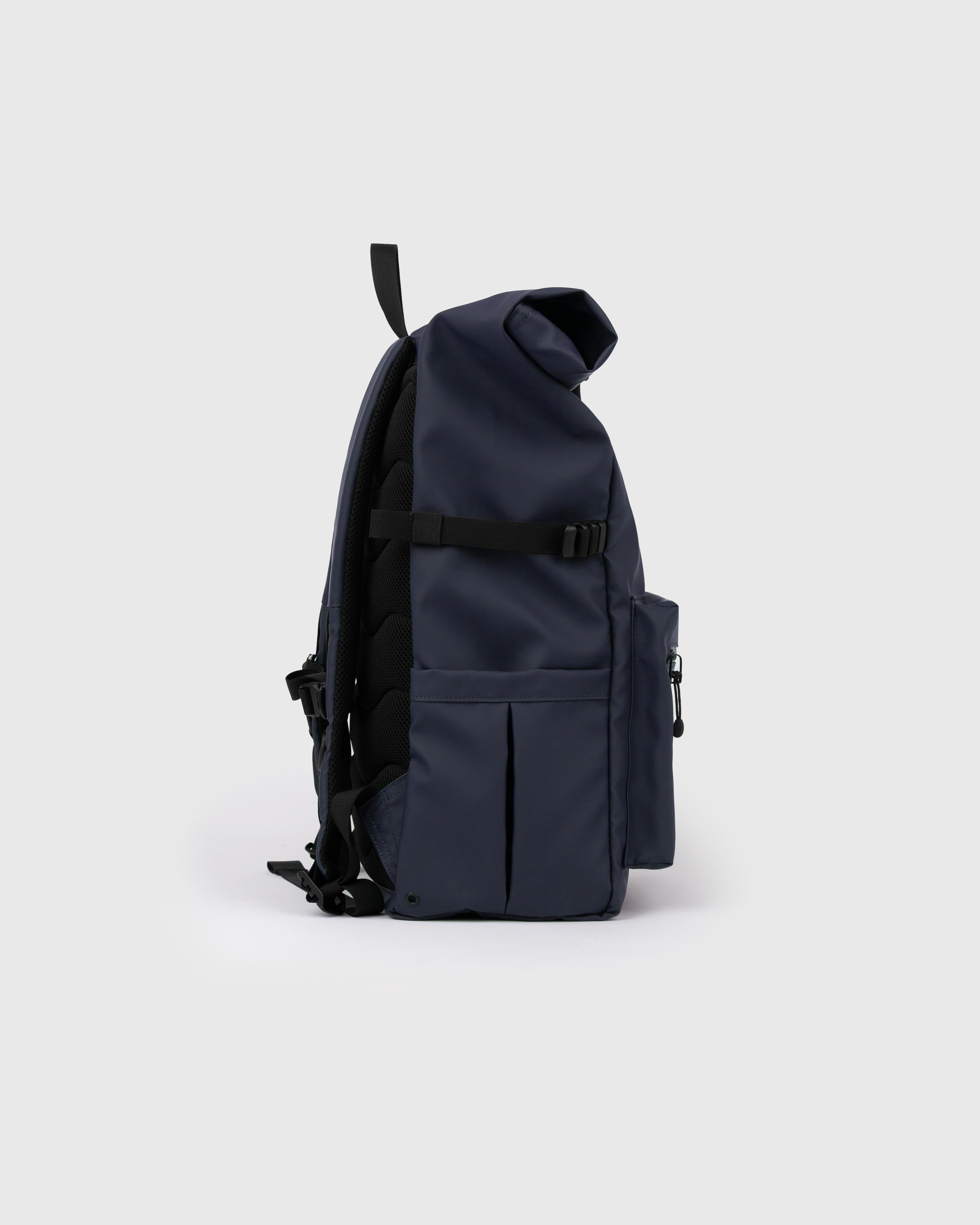 Sac à dos. Sandqvist STREAM Rolltop backpack L bleu foncé, vue latérale avec poignée supérieure, poche à l'avant, poche plaquée, sangle latérale et fermeture à enroulement.