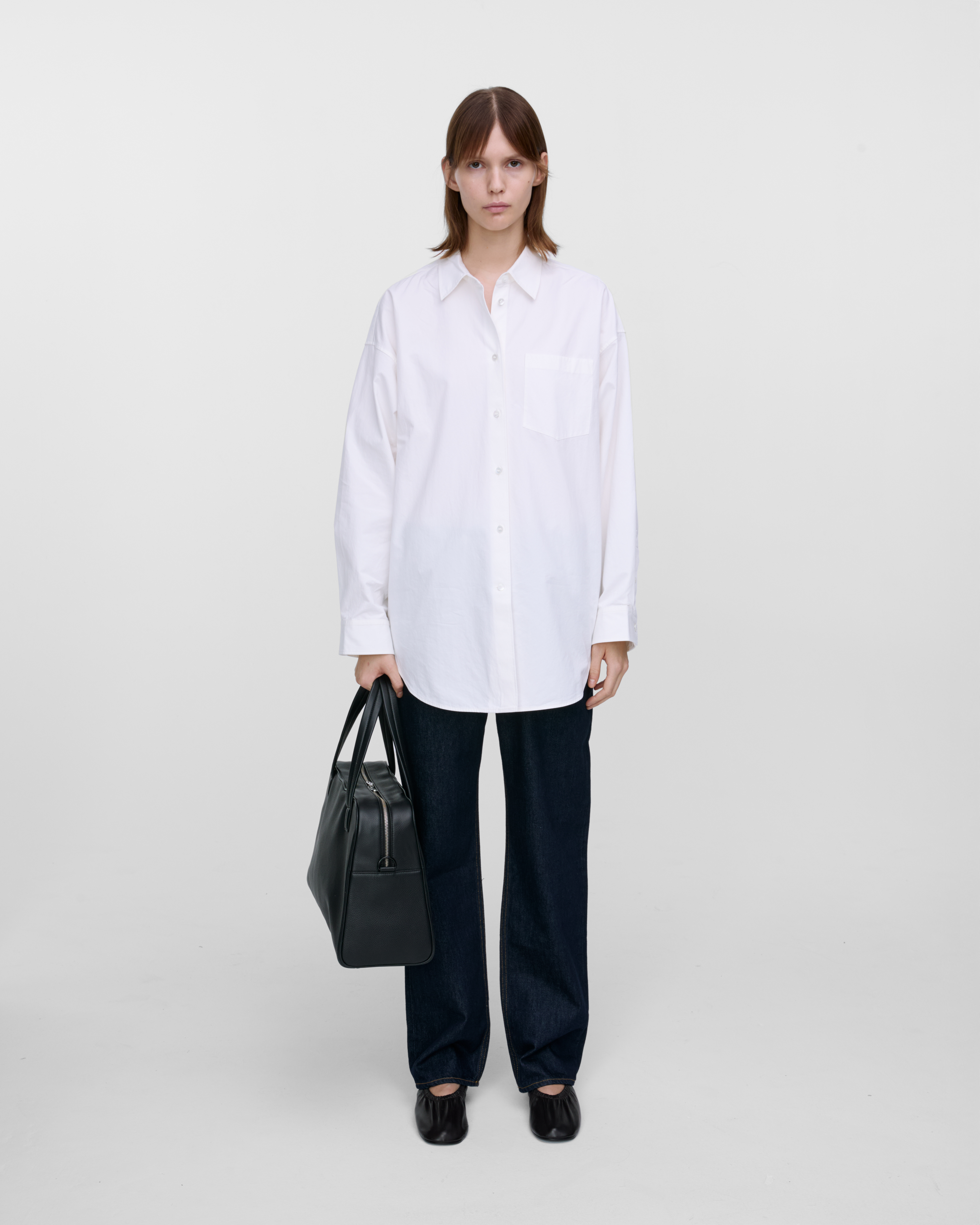 Female model holding the handbag Sandqvist LEATHER Bowling Bag Black in the hand. Front view showing fit and size.