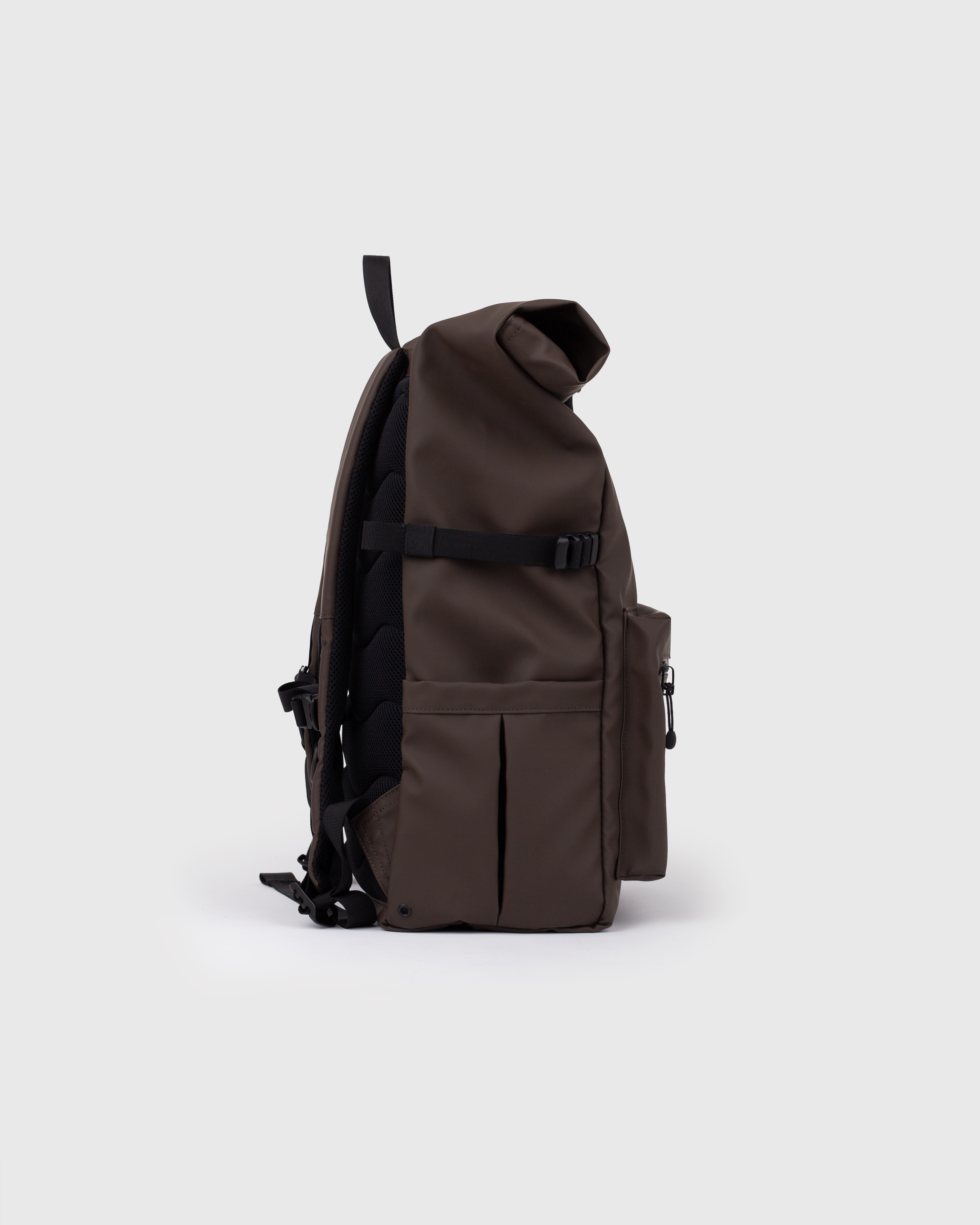 Sac à dos. Sandqvist STREAM Rolltop backpack L brun foncé, vue latérale avec poignée supérieure, poche à l'avant, poche plaquée, sangle latérale et fermeture à enroulement.