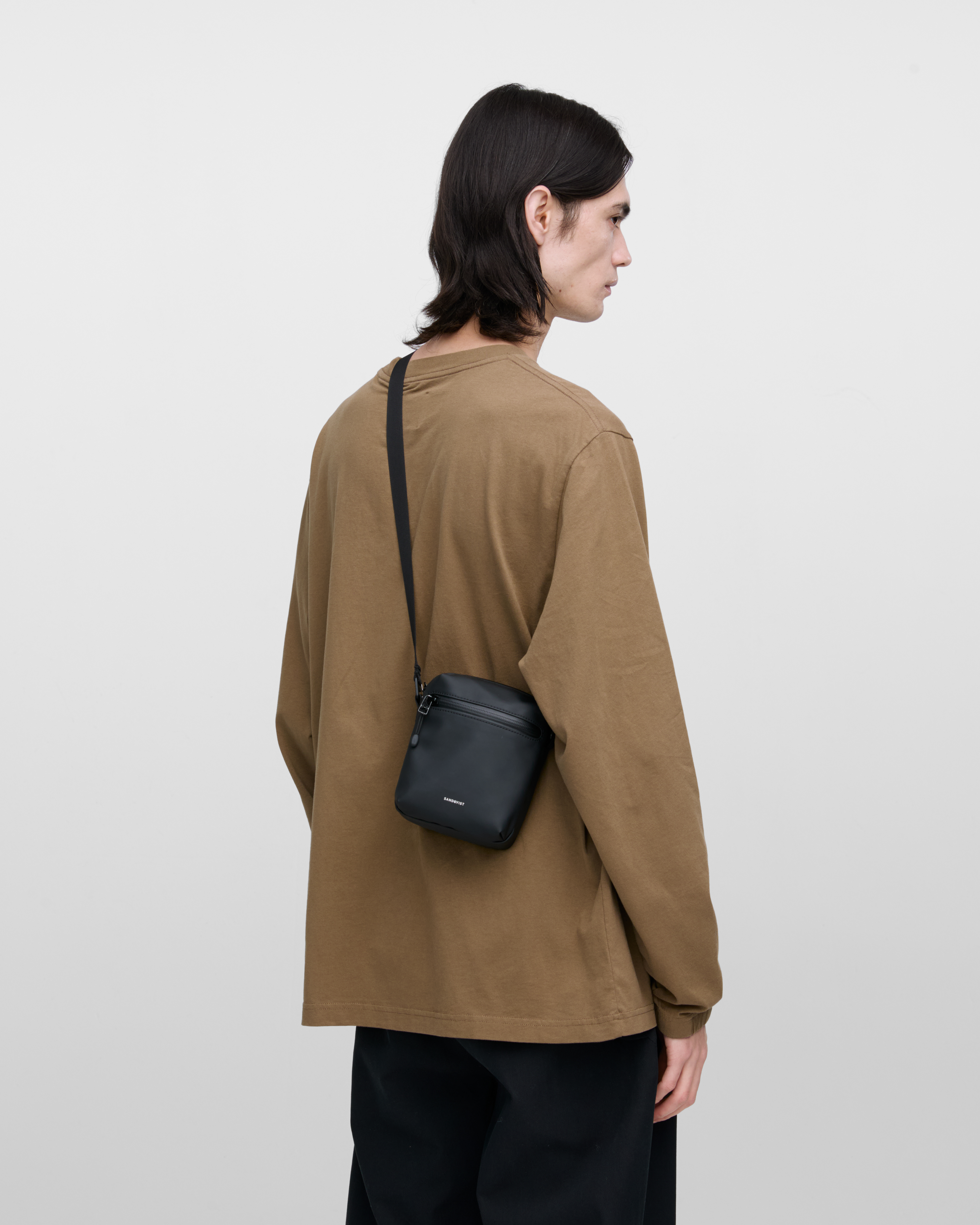 Sandqvist STREAM Shoulder Bag in black on a male model, back view showing fit and size.