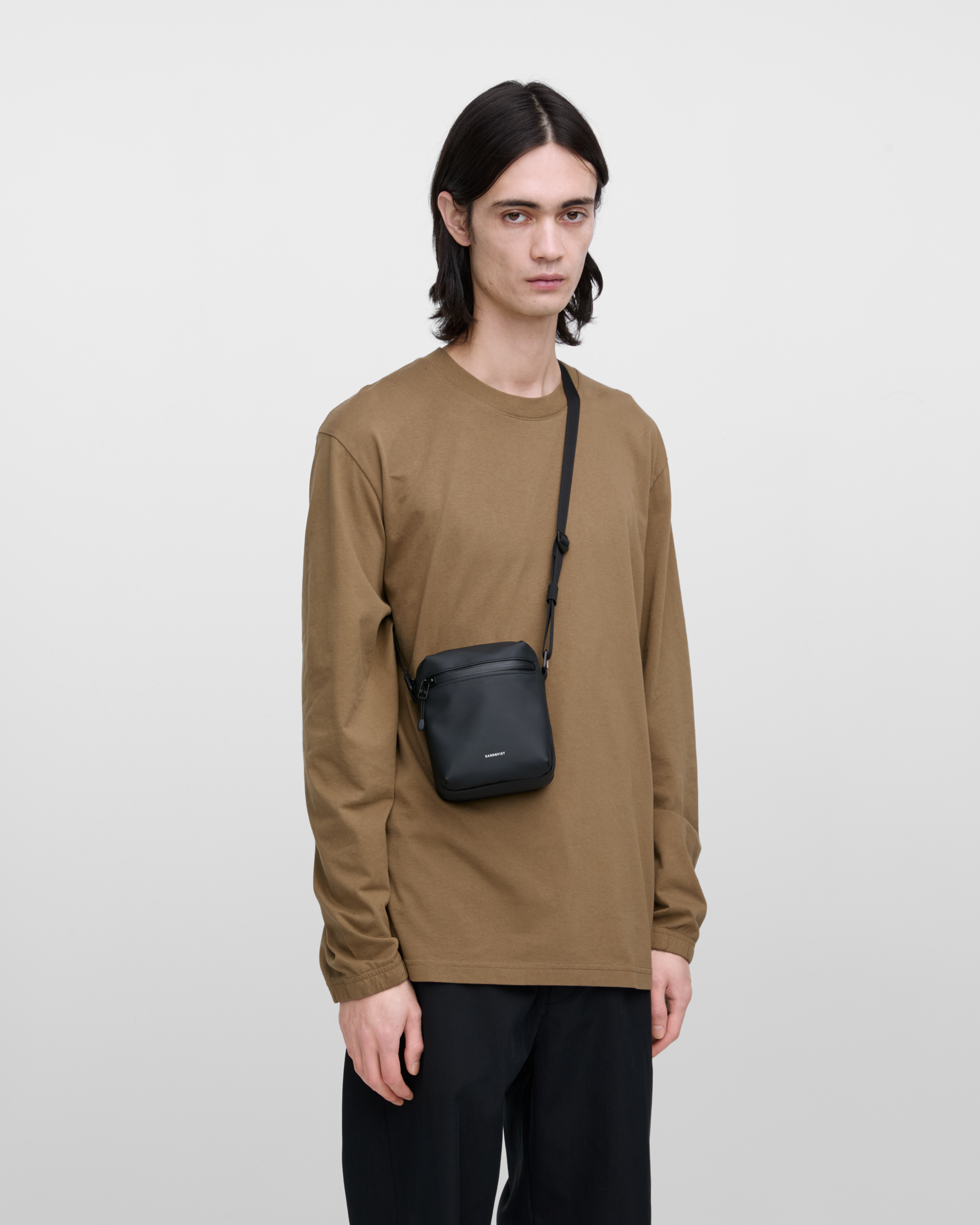 Sandqvist STREAM Shoulder Bag in black on a male model, front view showing fit and size.