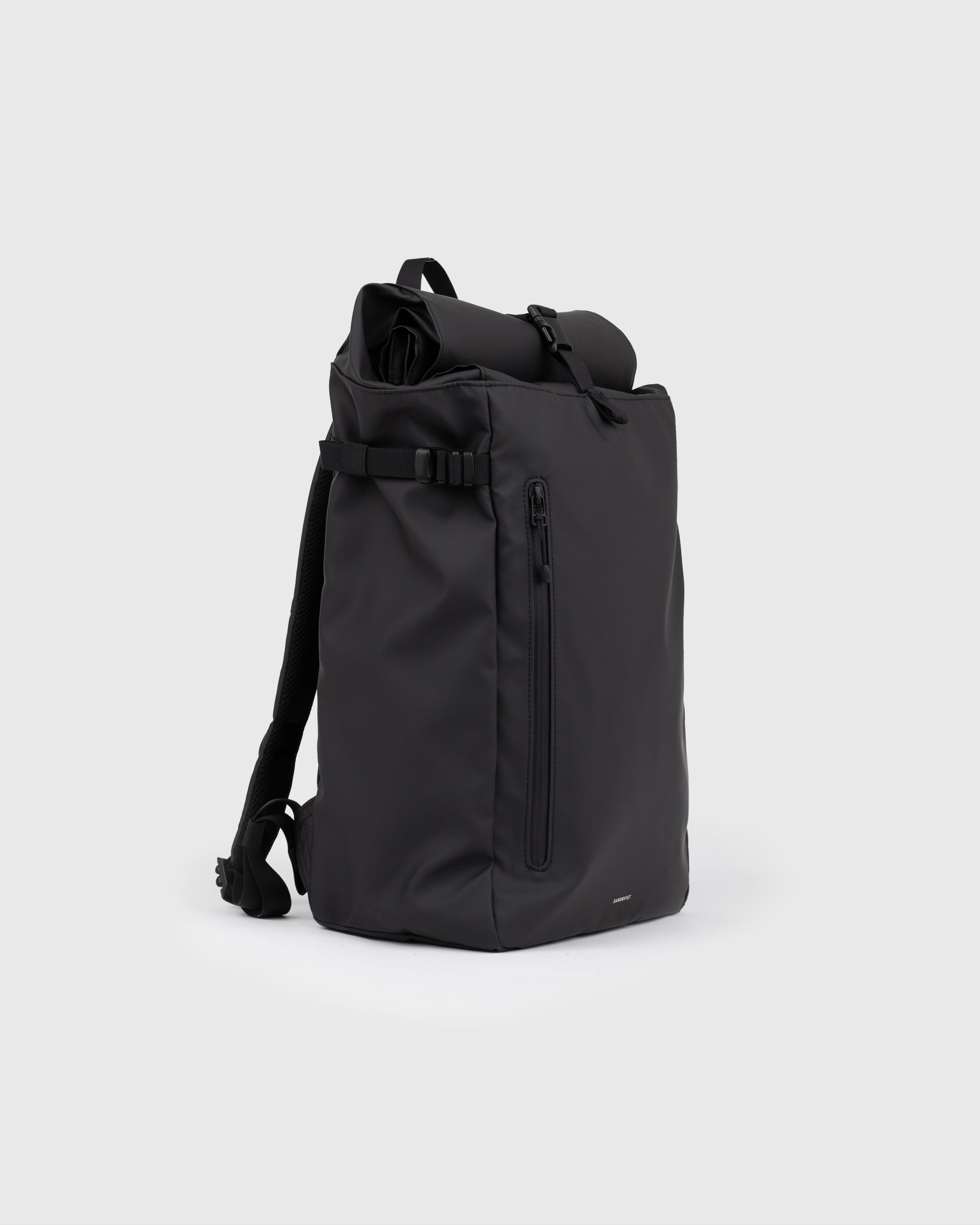 Sandqvist STREAM Slim Rolltop L backpack in black, side view with shoulder strap, top handle, zipper pocket at front and rolltop closure.