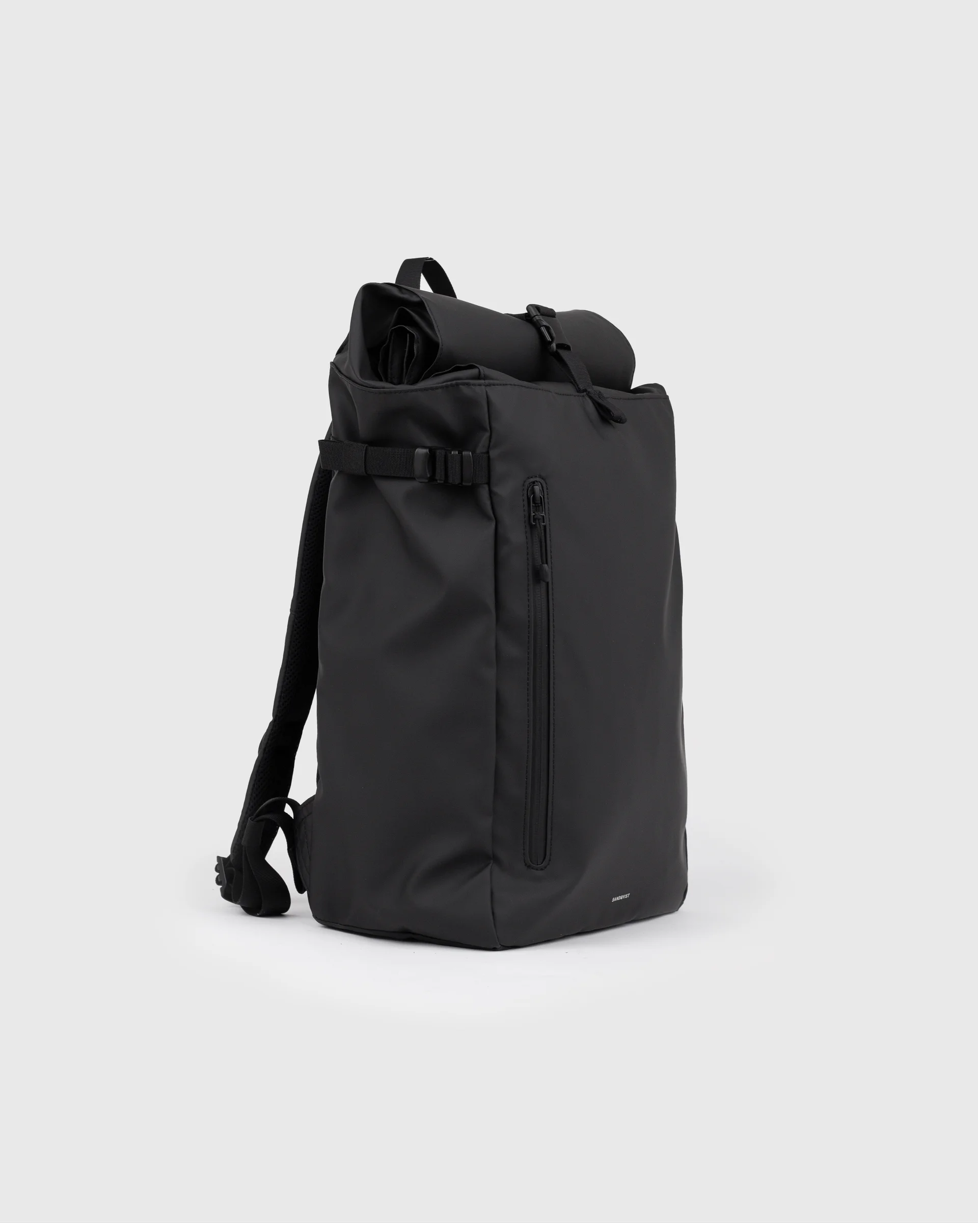 Sandqvist STREAM Slim Rolltop L backpack in black, side view with shoulder strap, top handle, zipper pocket at front and rolltop closure.