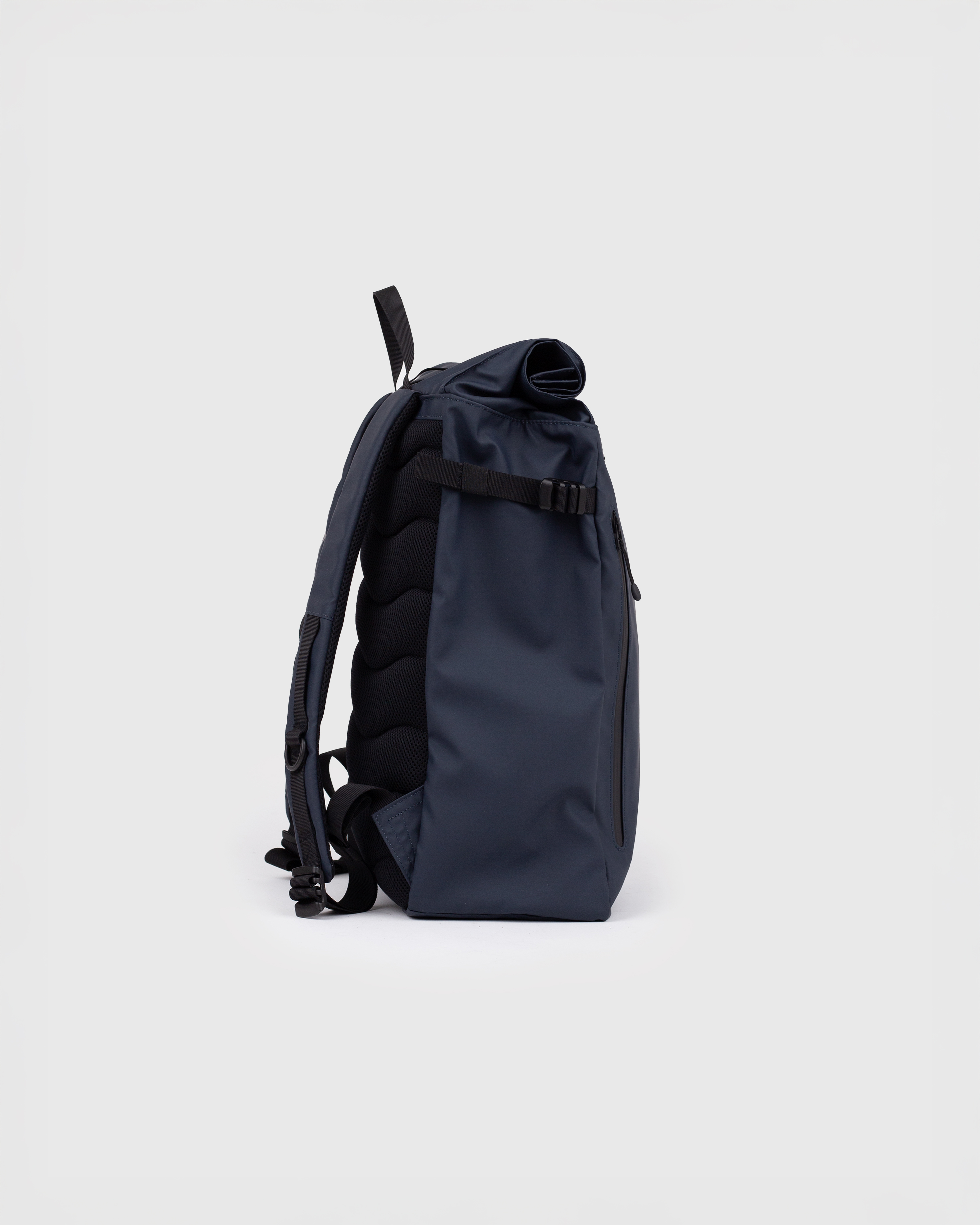 Sac à dos Sandqvist STREAM Slim Rolltop M bleu marine, vue latérale avec bandoulière, poignées supérieures et fermeture à enroulement.