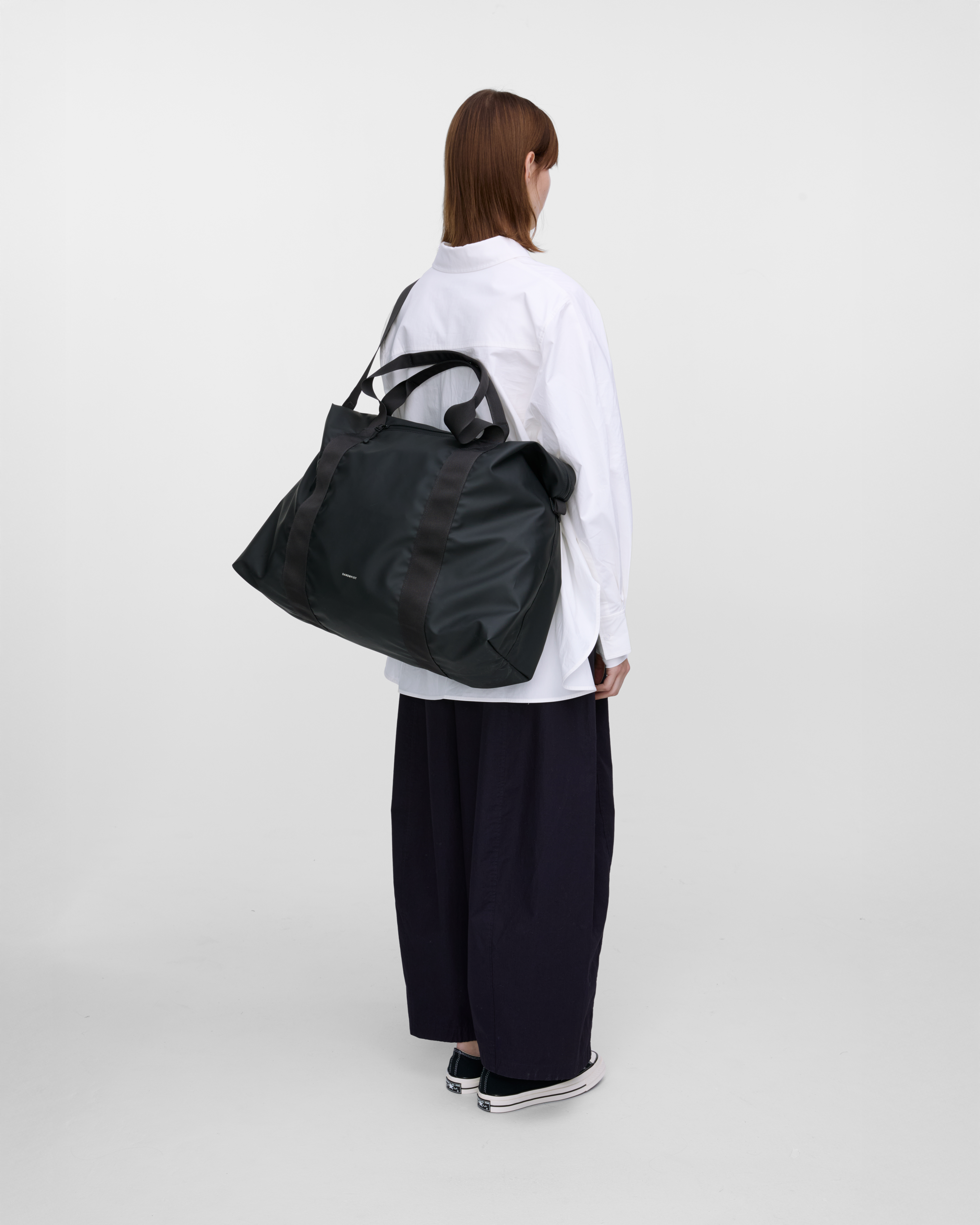 Model wearing Sandqvist Weekender Bag, Black, view from the back showing fit and size hanging over the shoulder across the back.